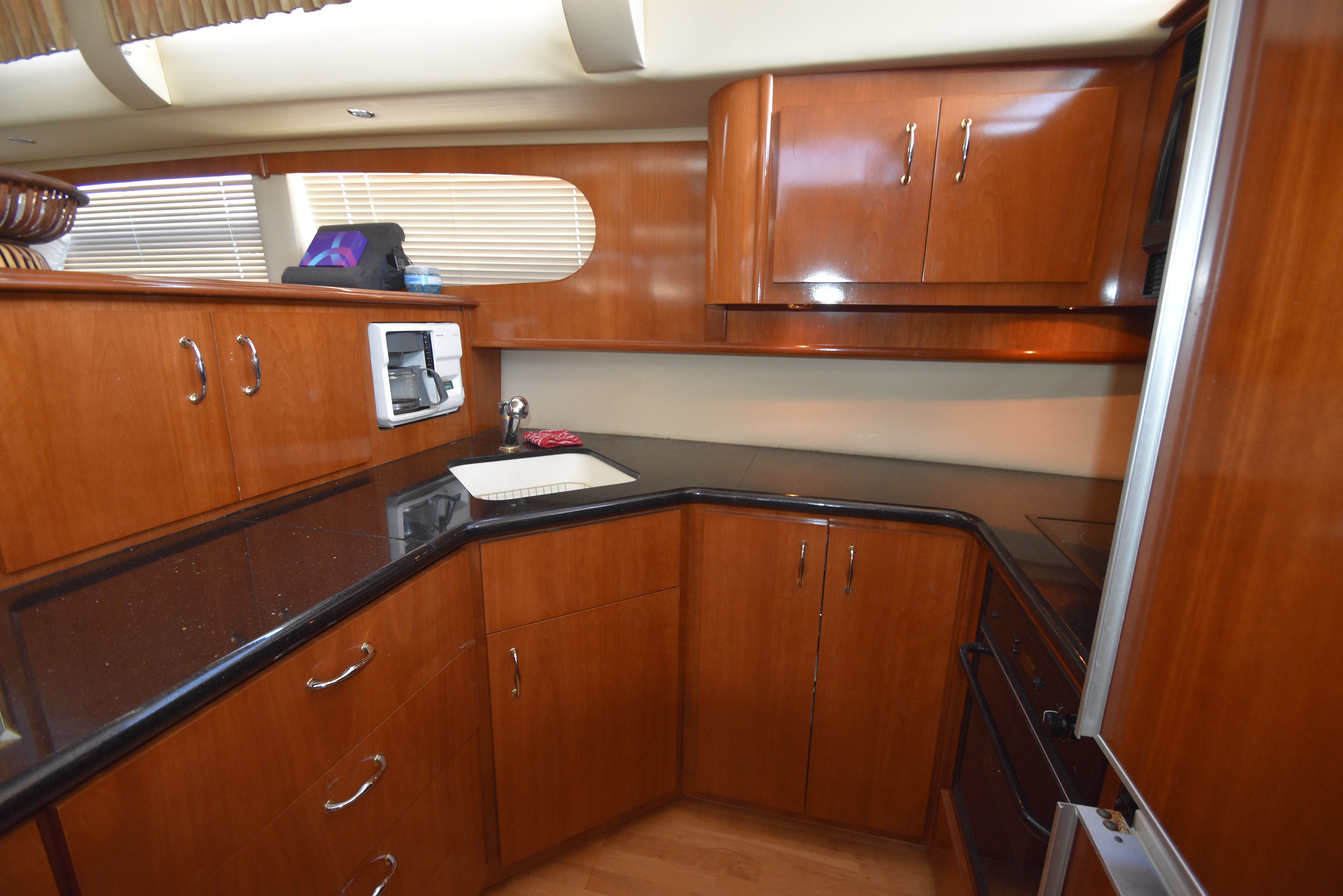 Interior view of a modern yacht kitchen with wooden cabinets and black countertops.