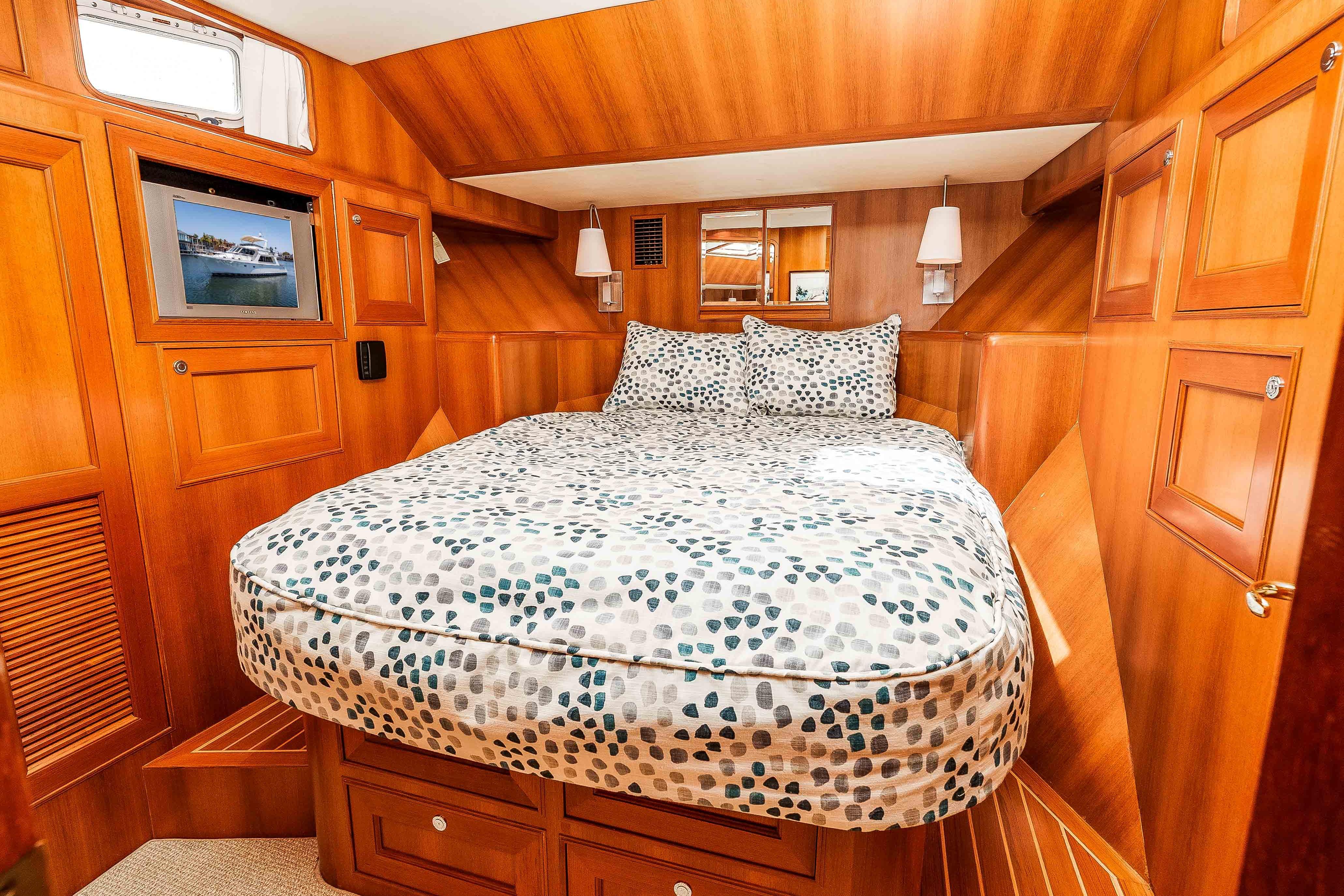 Luxurious 2005 Offshore Yachts 54 Pilothouse cabin with cozy bed and elegant wood paneling.