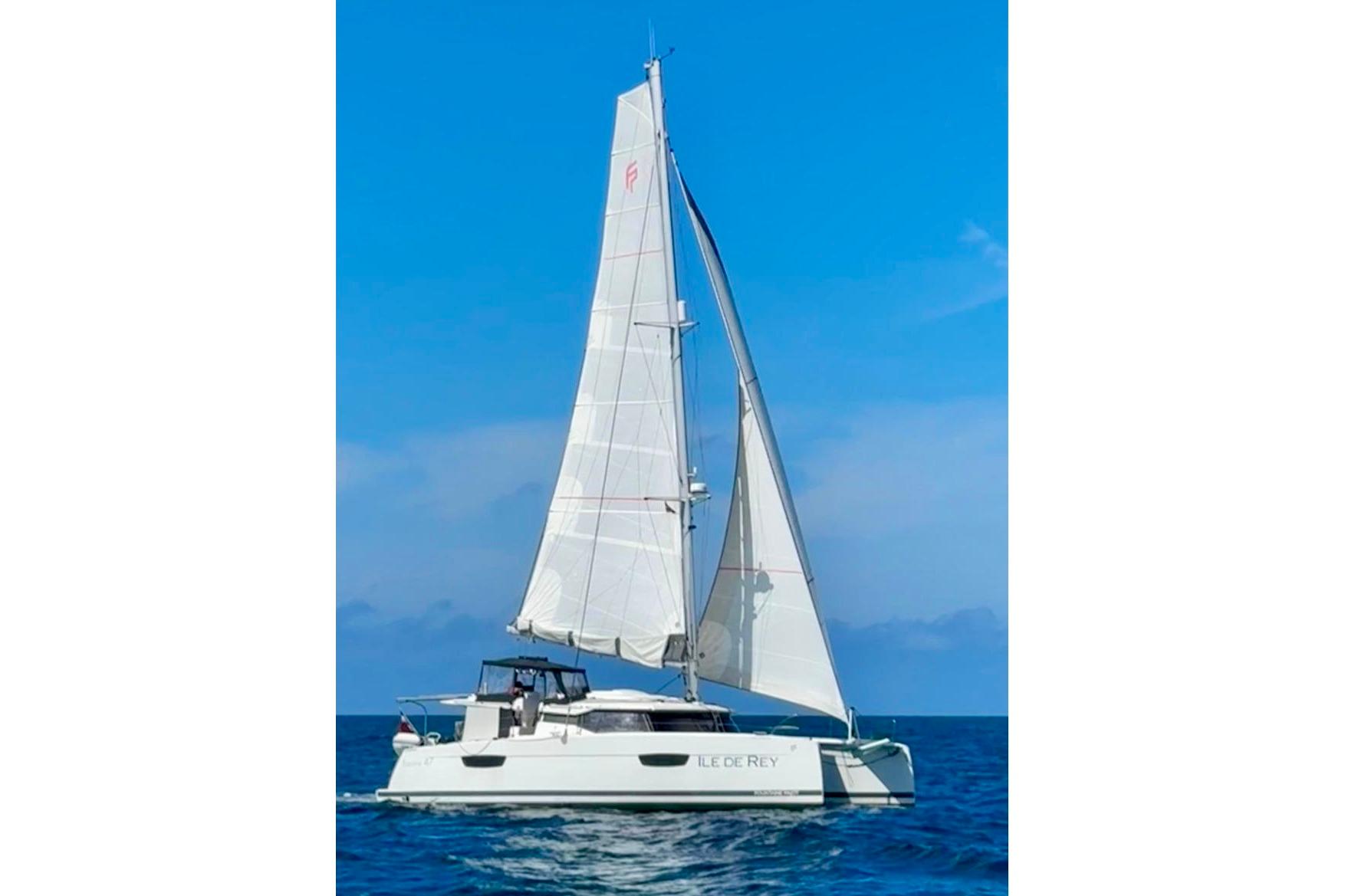 2020 Fountaine Pajot Saona 47 sailing catamaran on open sea under clear blue sky.