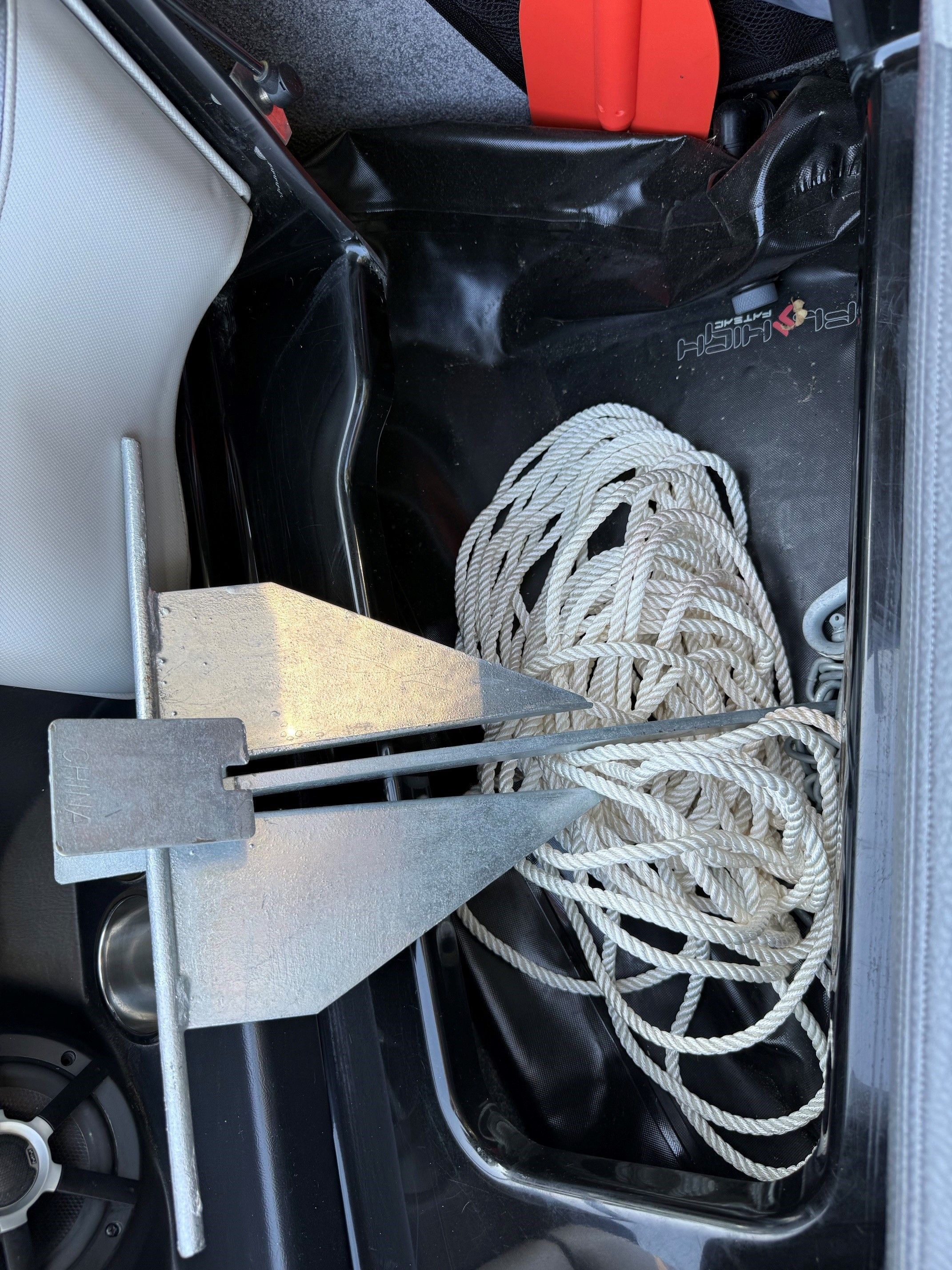 An anchor with rope in a boat's storage compartment.