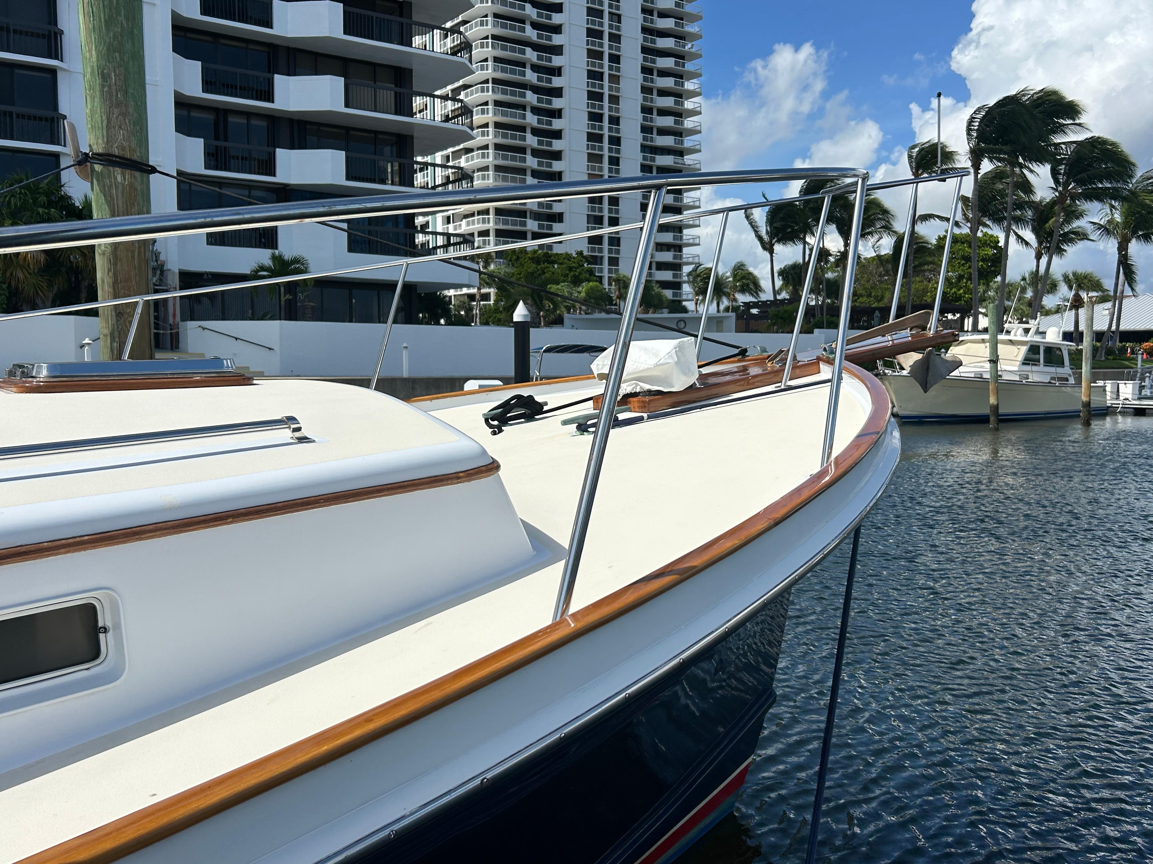 1987 Lyman-Morse Downeast Flybridge boat docked near modern buildings and palm trees.