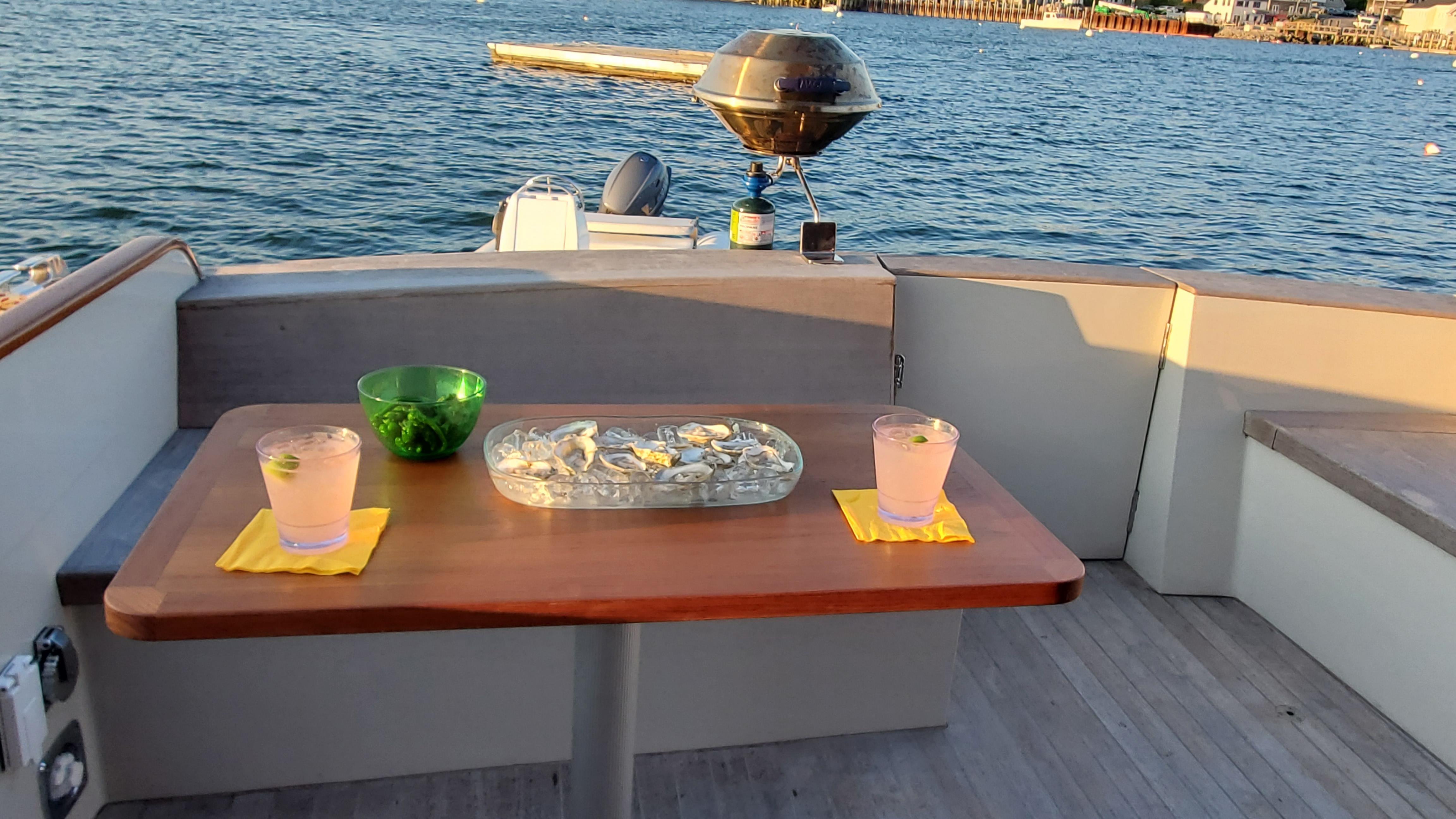 1997 Lyman-Morse Custom Flybridge yacht with drinks and snacks on deck, overlooking the ocean.
