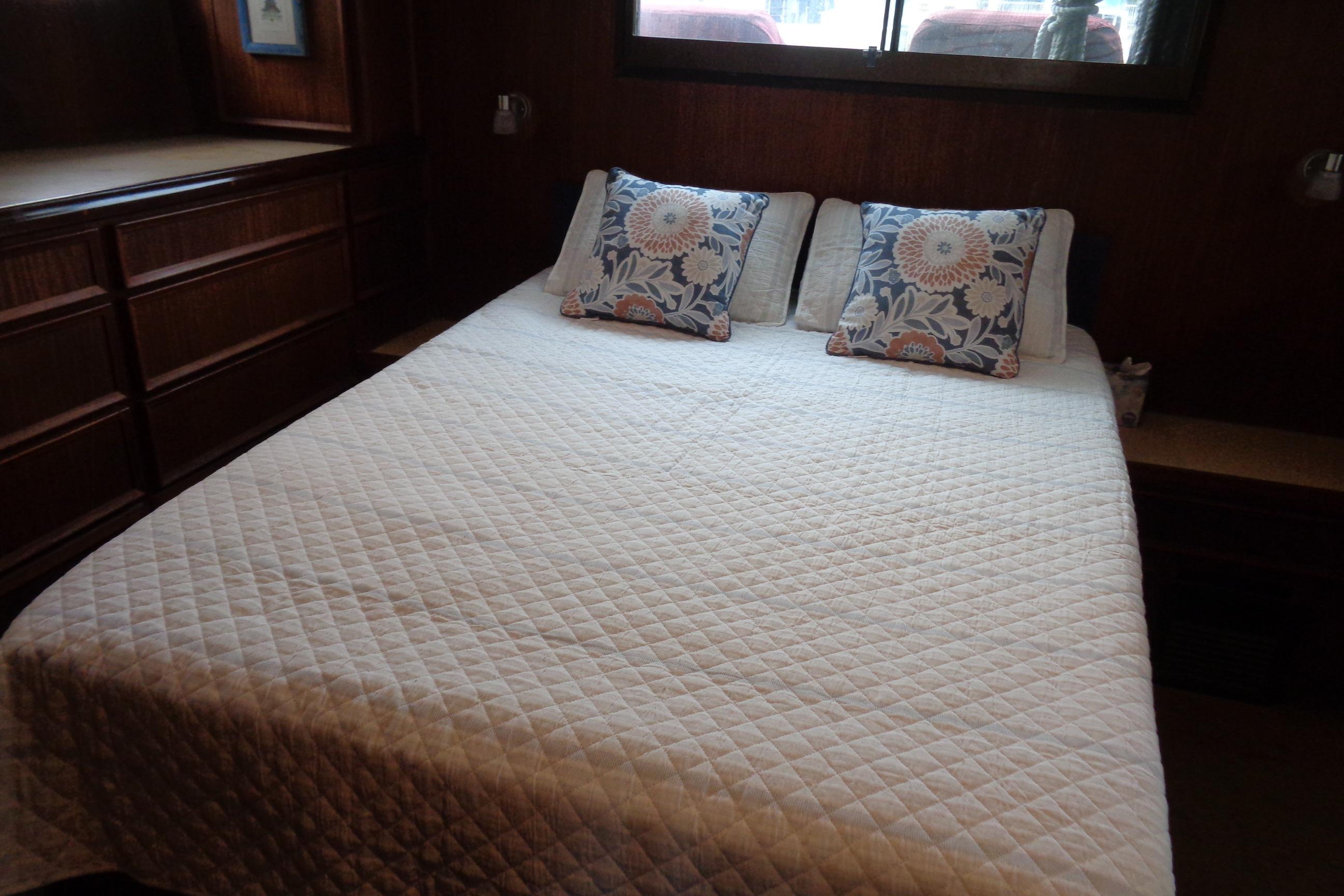 Cozy bedroom in 1981 Hatteras 48 Cockpit Motor Yacht with floral pillows and quilted bedding.