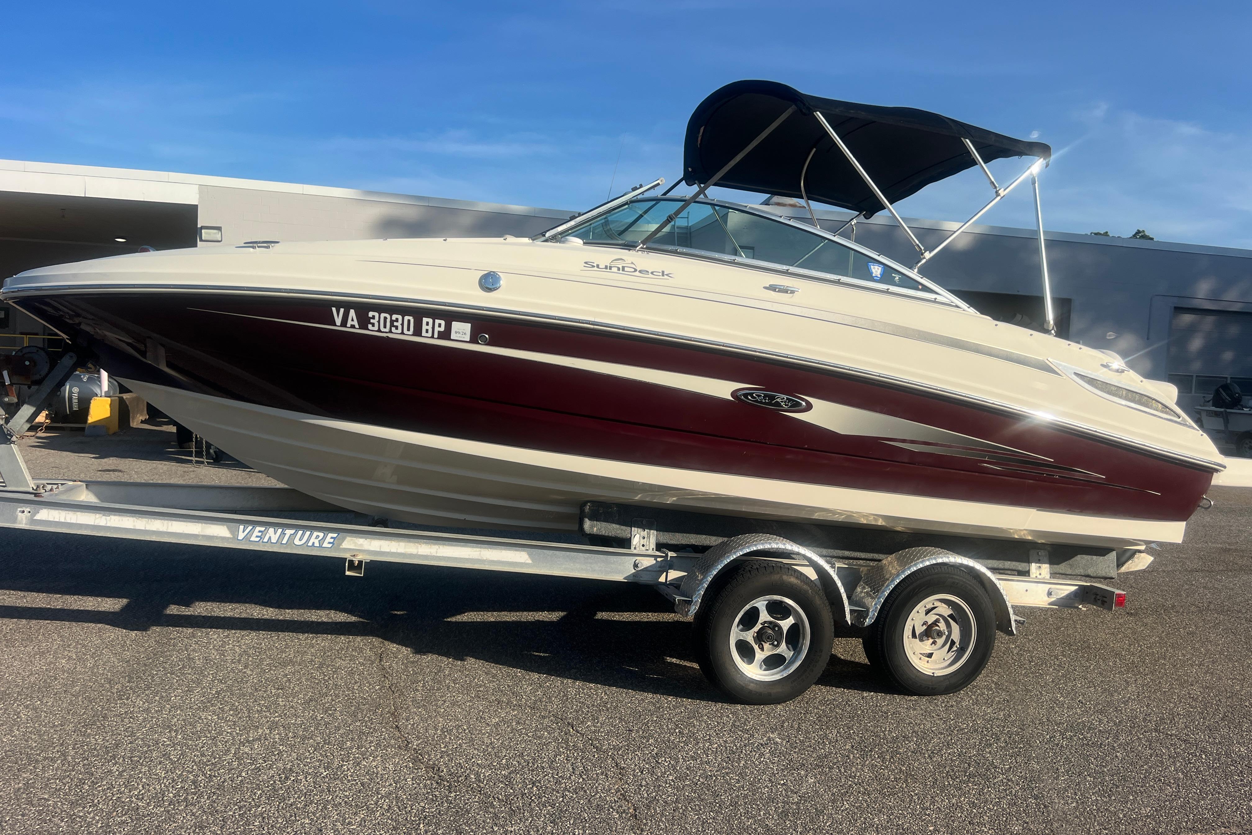 2009 Sea Ray 210 Sundeck boat on trailer, parked outdoors under clear sky.