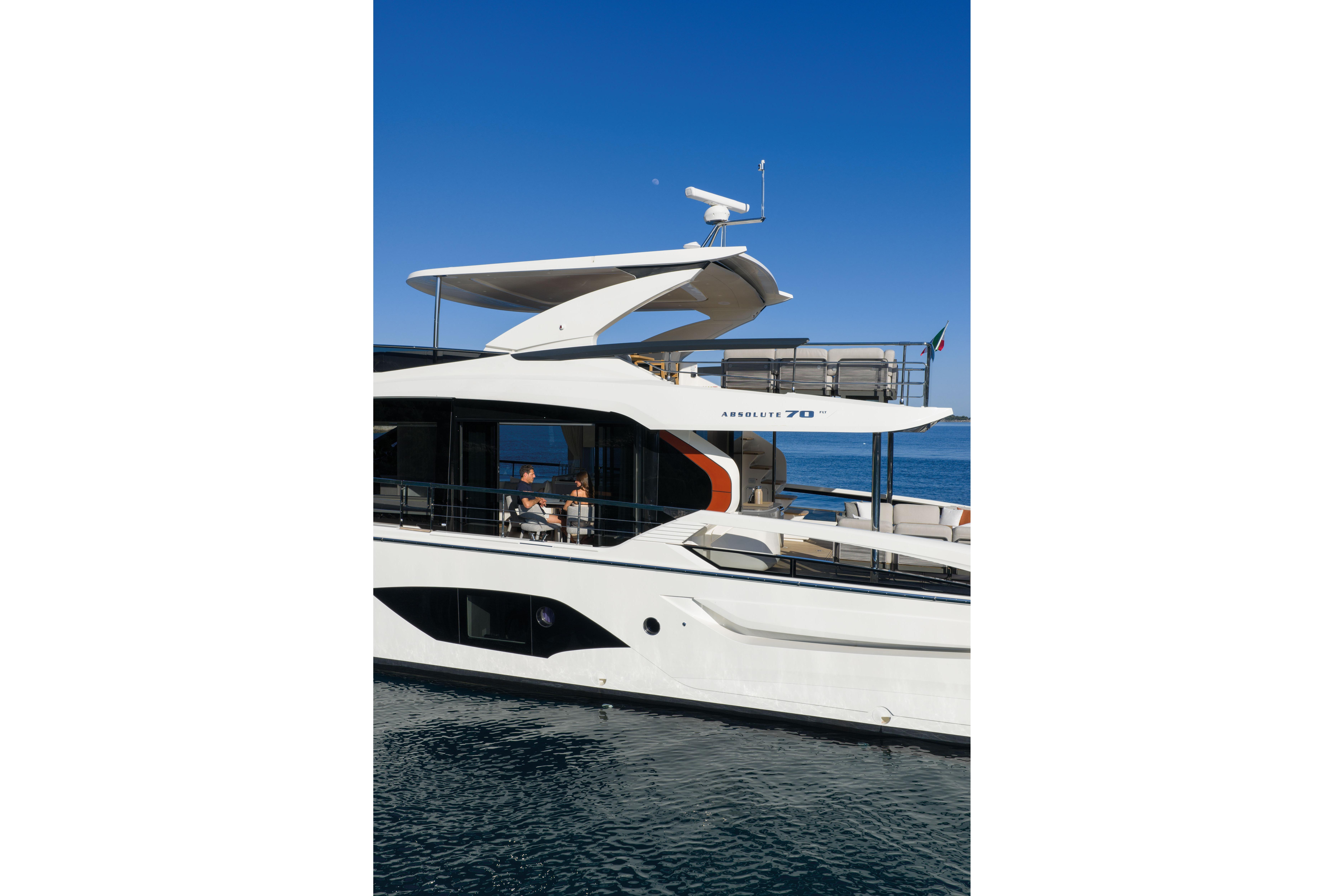 Luxury yacht with modern design on calm water, blue sky in the background.