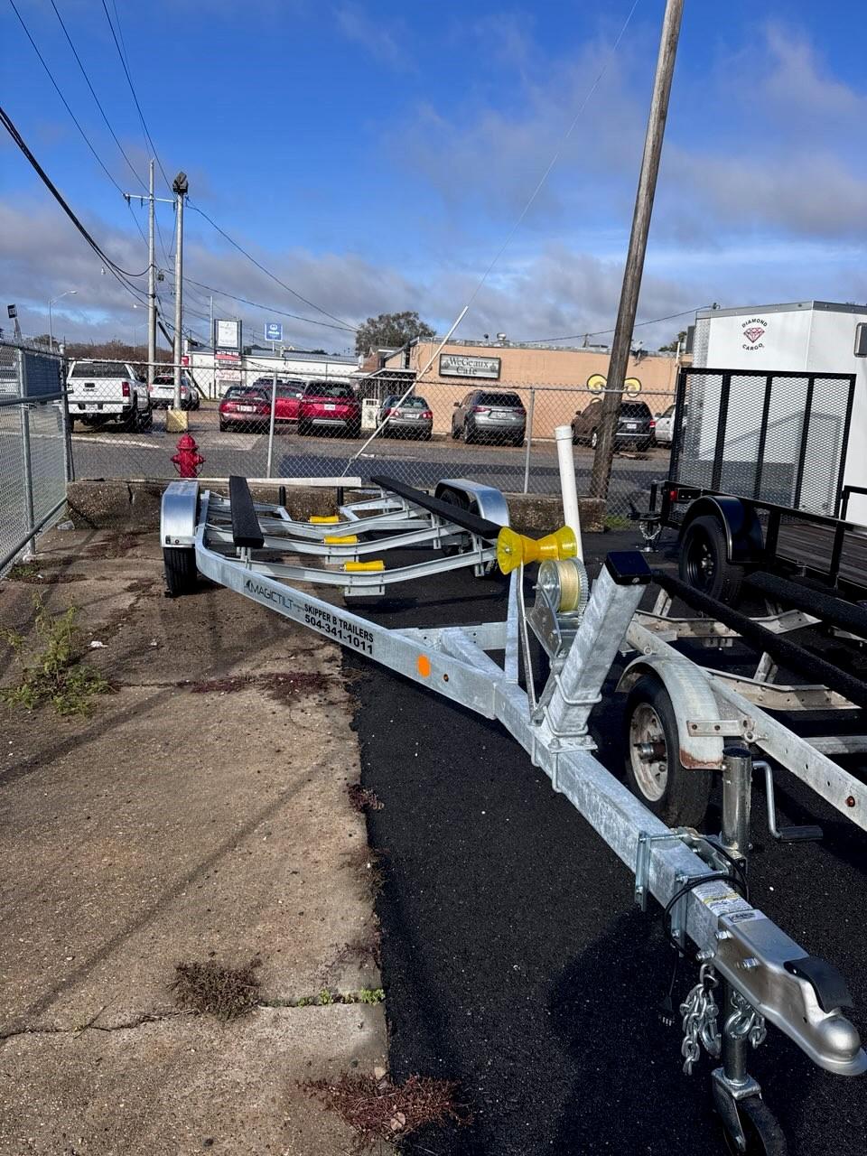 1963 Chris-Craft Sportsman boat trailer parked outdoors on asphalt near industrial buildings.