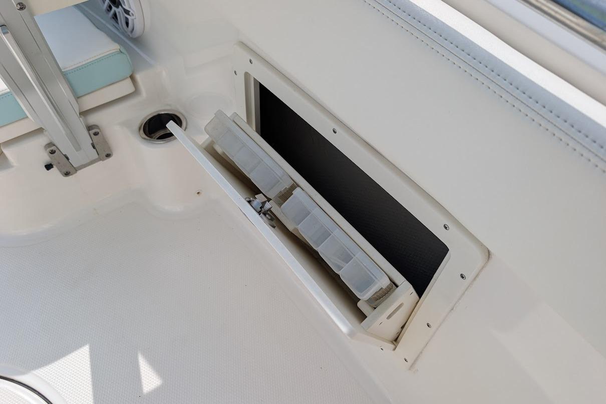 Storage compartment on 2022 Robalo R242 Explorer boat, featuring organized tackle boxes.