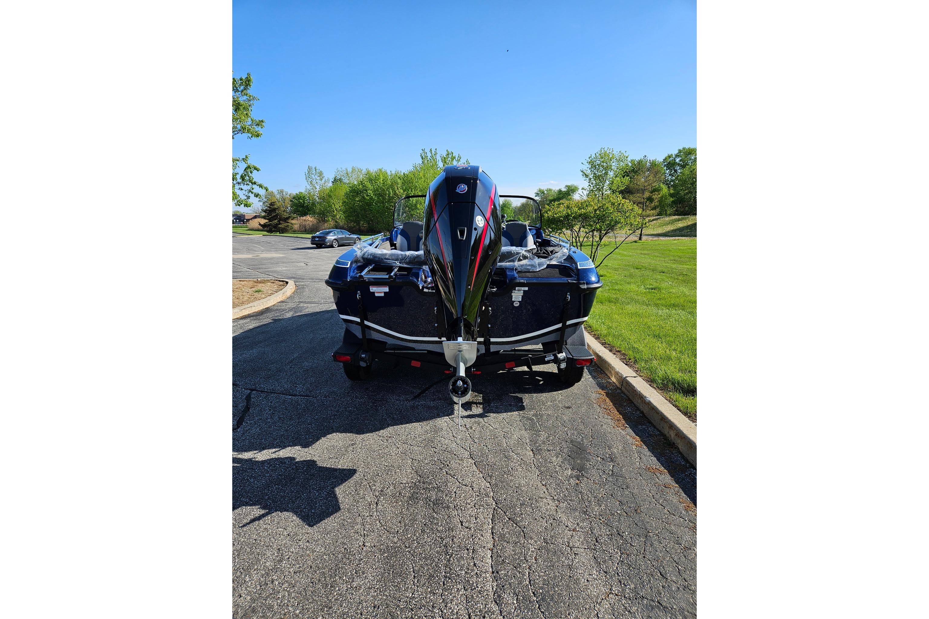 2026 Nitro ZV19 Sport Pro boat parked on asphalt, surrounded by greenery and clear blue sky.