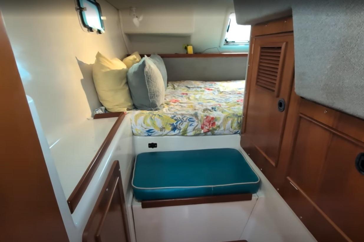 Cozy cabin interior of 2004 PDQ 34 Powercat with floral bedding and wooden cabinetry.