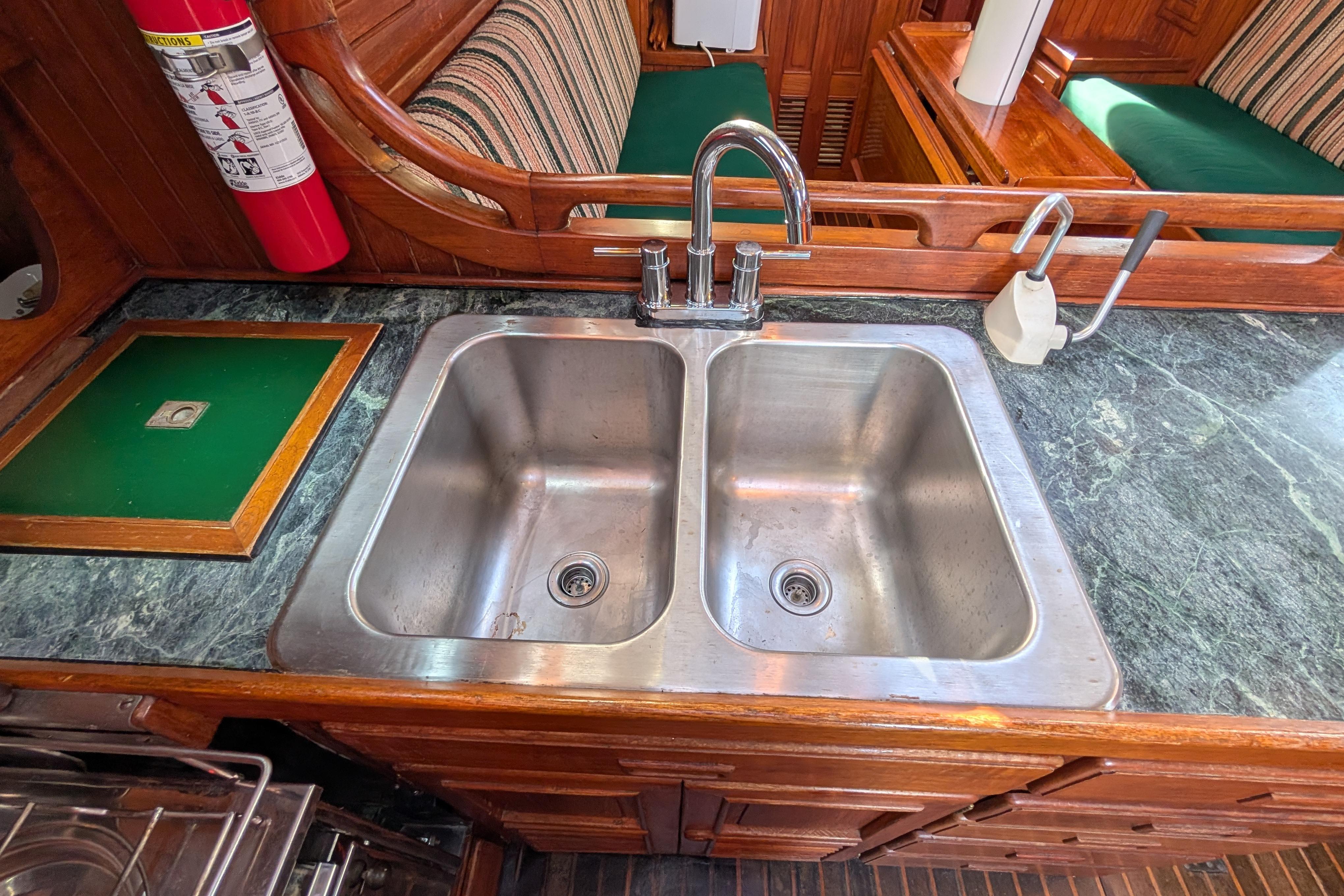 Stainless steel double sink in 1983 Robert Perry 41 yacht kitchen, with marble countertop.
