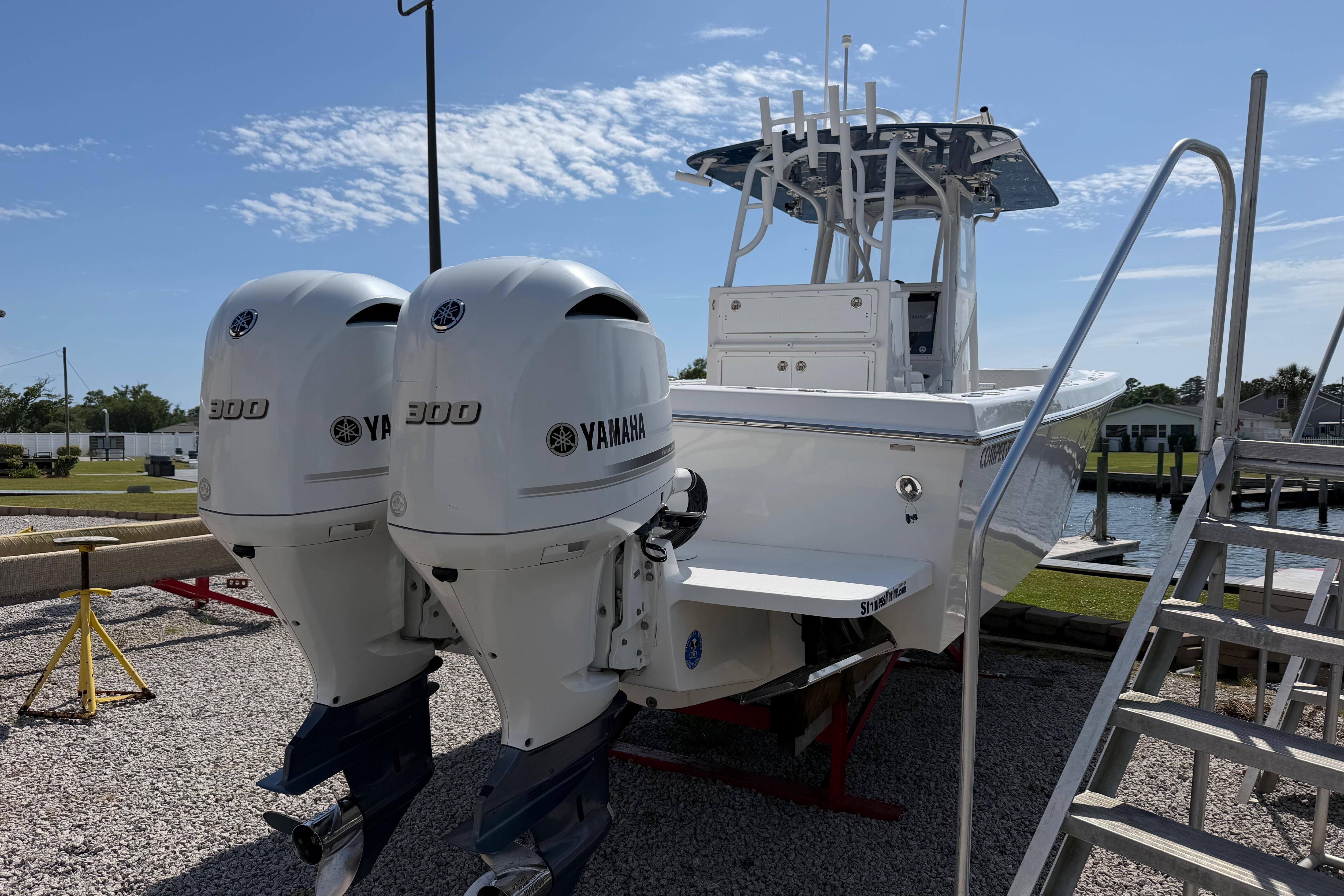 2021 Competition 31 boat with twin Yamaha 300 engines, docked on gravel.
