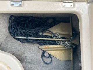 An anchor with chain and rope in a boat's storage compartment.