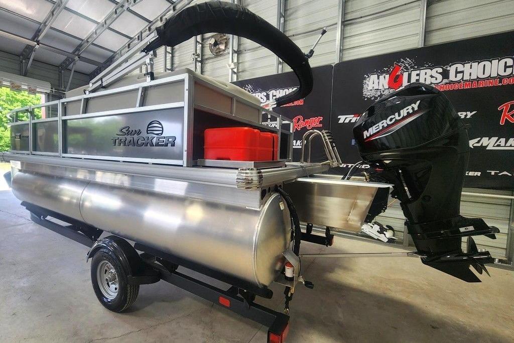 2026 Sun Tracker Bass Buggy 16 DLX pontoon boat with Mercury outboard motor in showroom.