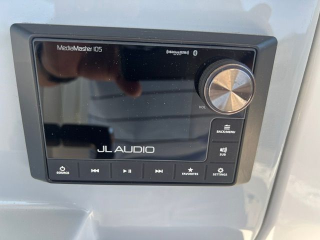 A JL Audio MediaMaster 105 control unit with volume knob and various control buttons.