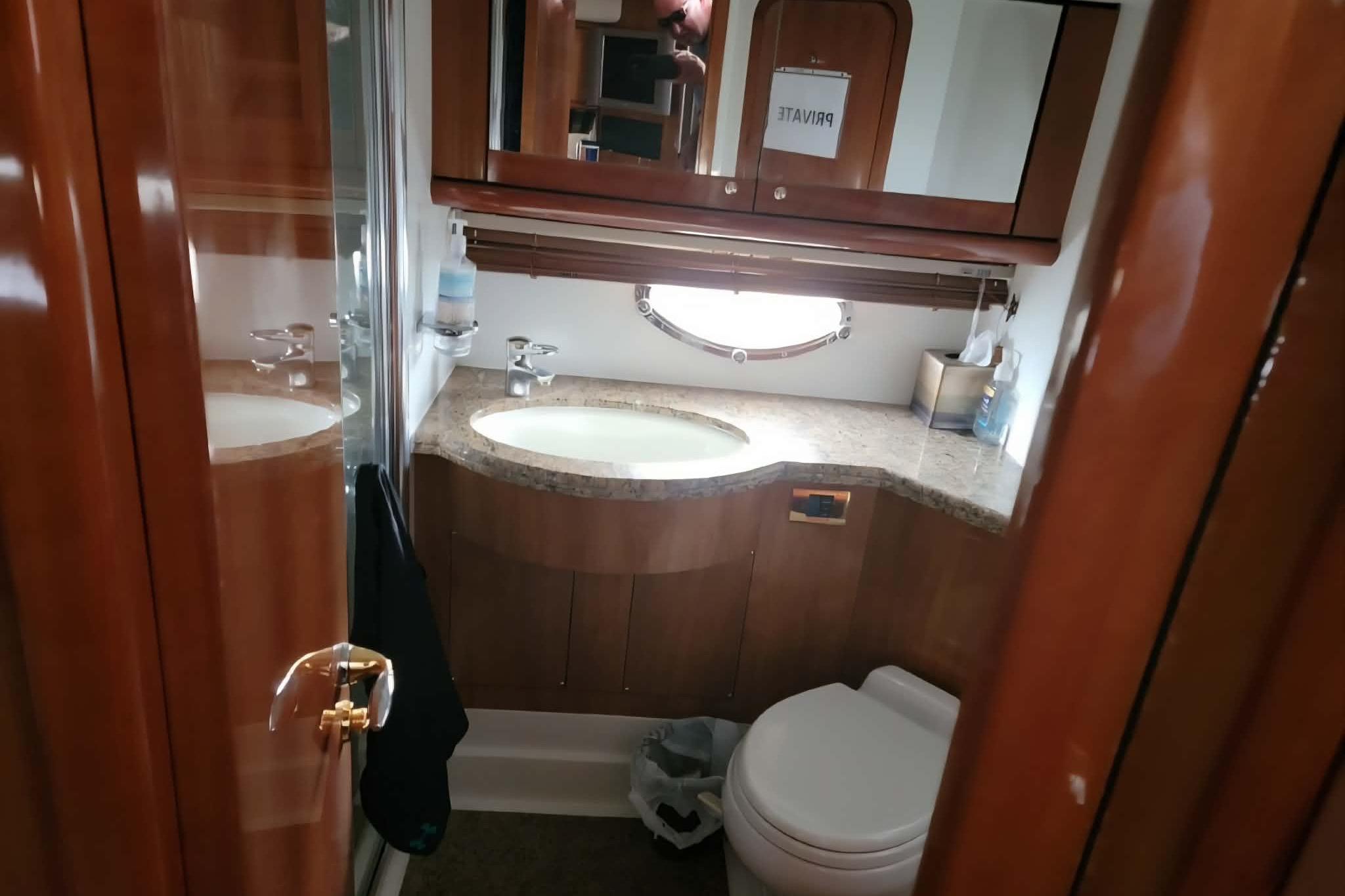 Luxurious bathroom in 2004 Sunseeker Predator 56 yacht with wooden cabinetry and modern fixtures.