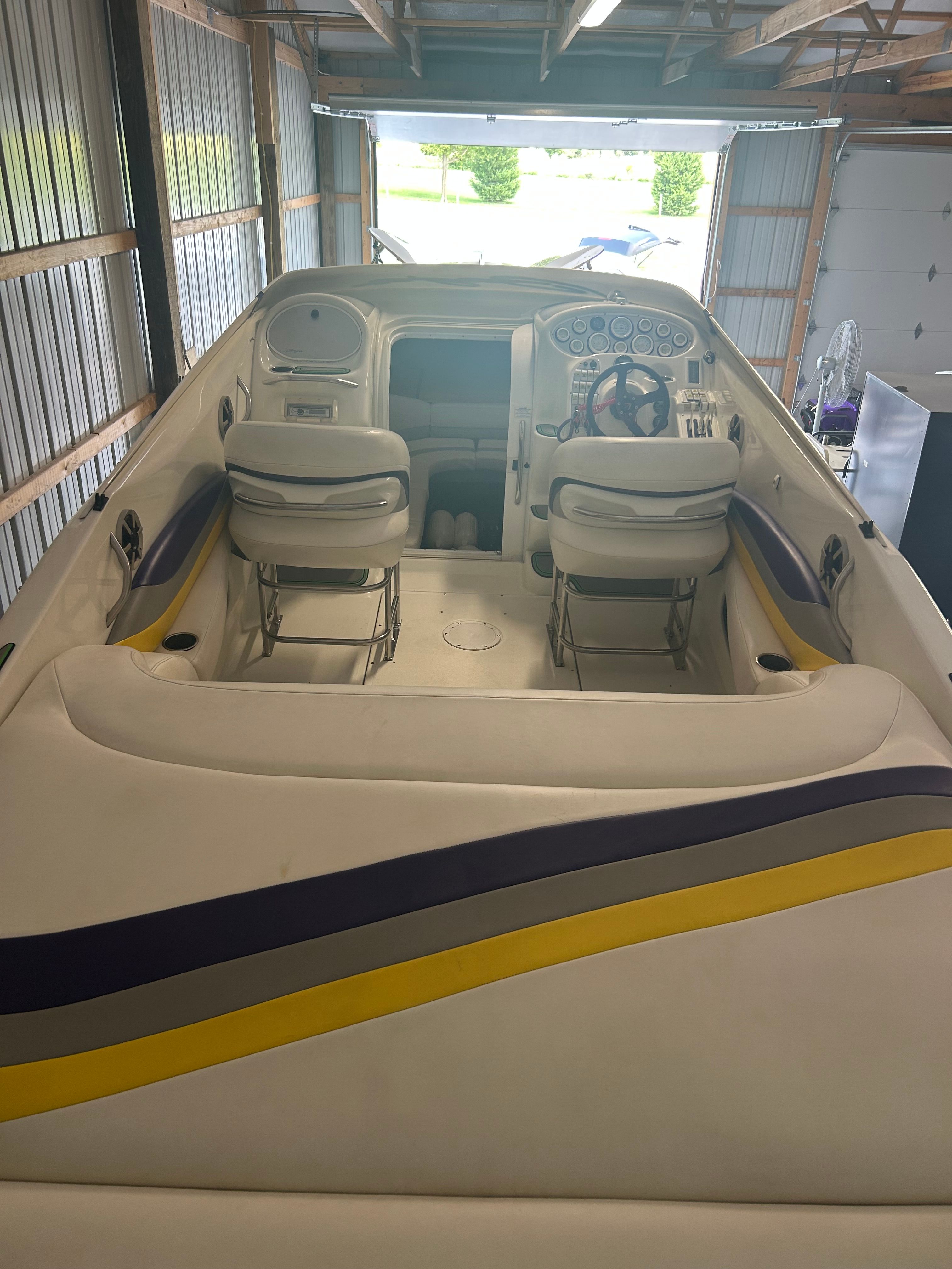 The image shows the cockpit of a 1996 Baja 302 boat in a garage.