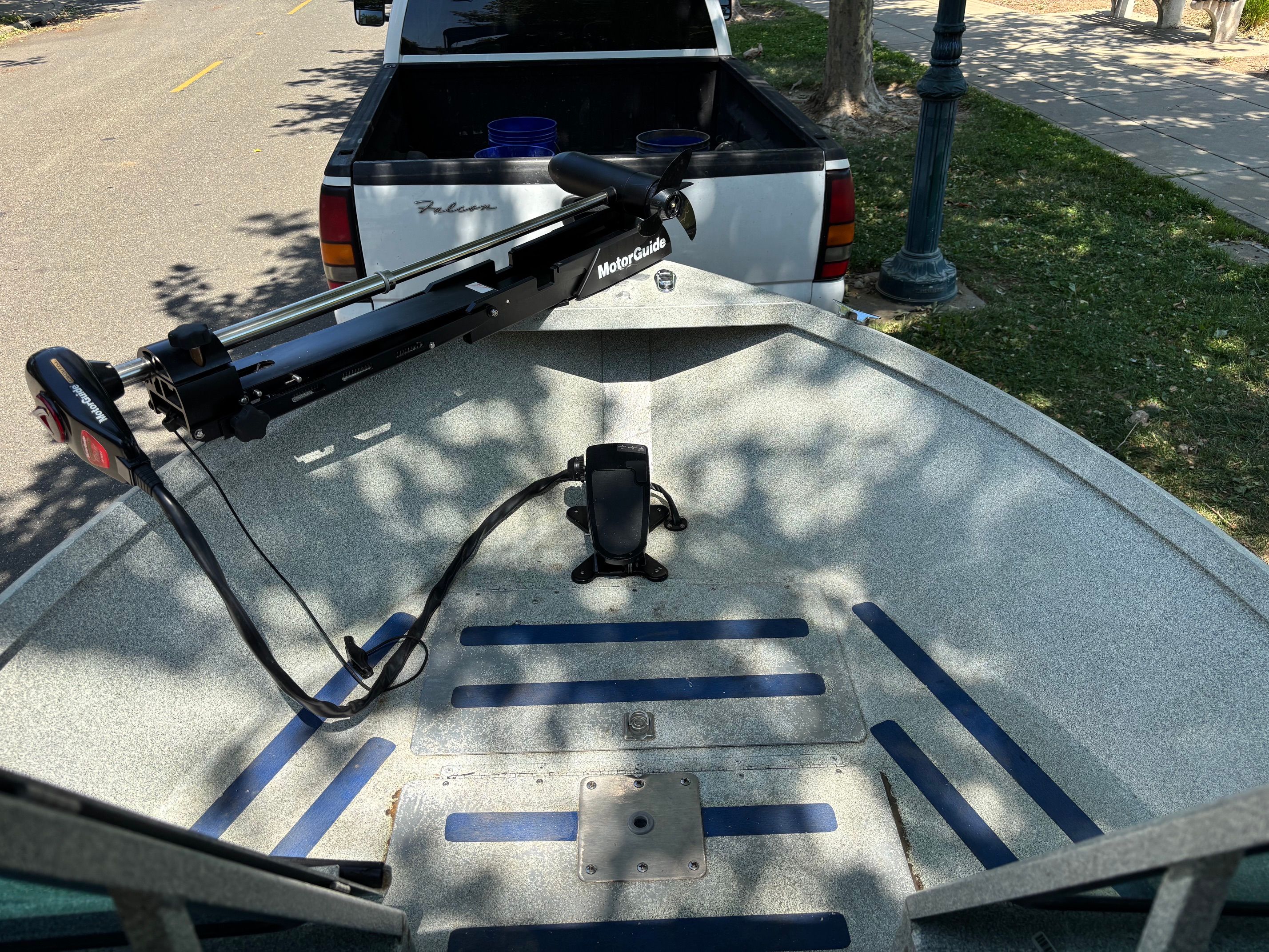 A 2002 Stryker Rogue boat with a Minn Kota motor, parked next to a pickup truck.