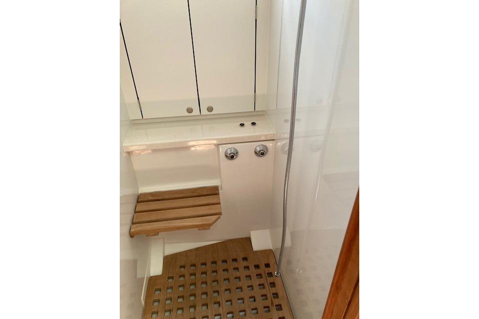 Shower area in 2019 Delphia BluEscape 1200 yacht with wooden seat and floor.