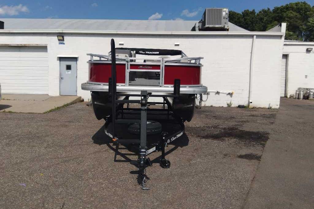 2026 Sun Tracker Bass Buggy 18 DLX pontoon boat on trailer in parking lot.