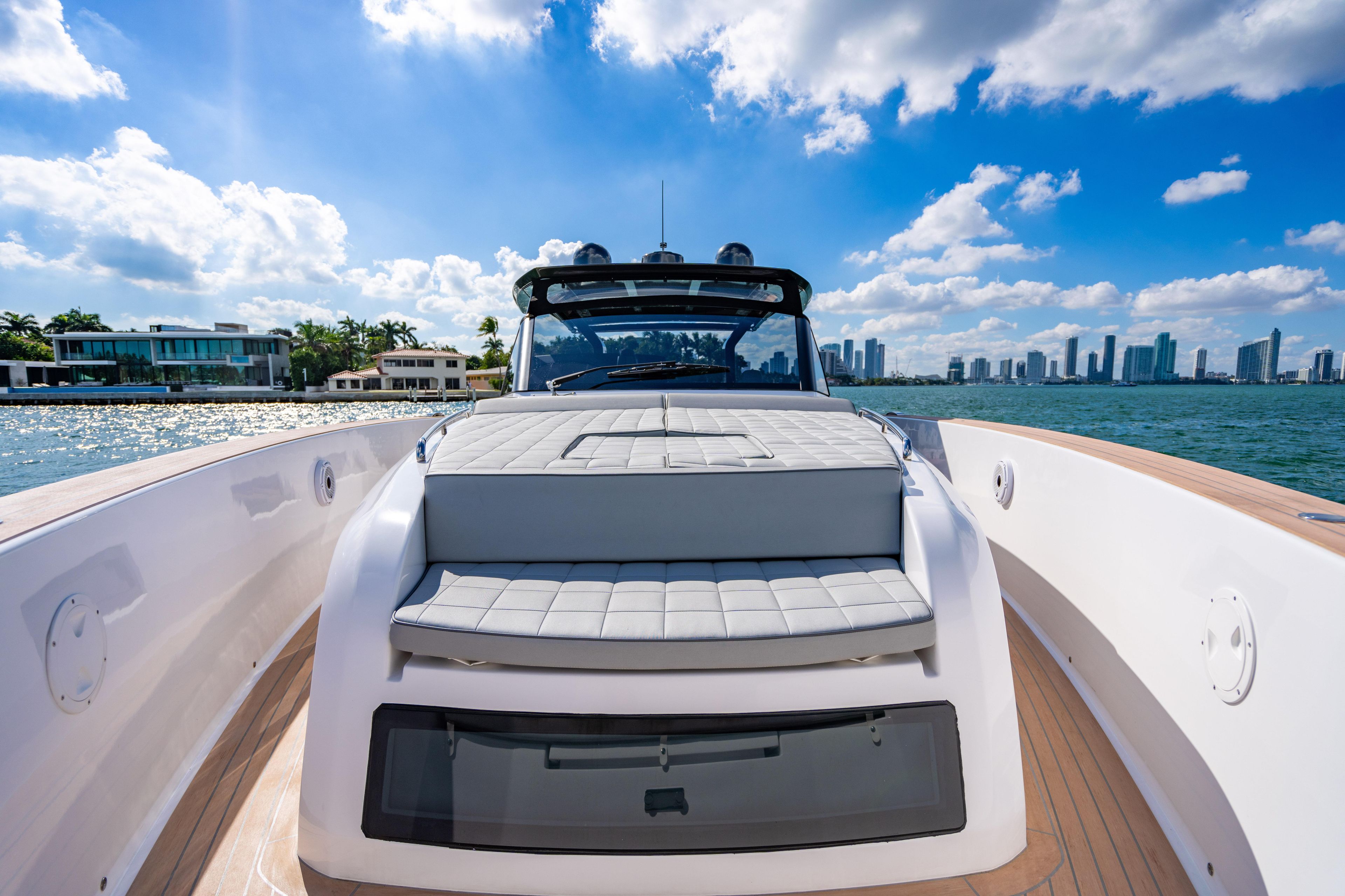 2023 Pardo 50 yacht cruising near modern waterfront homes under a blue sky.