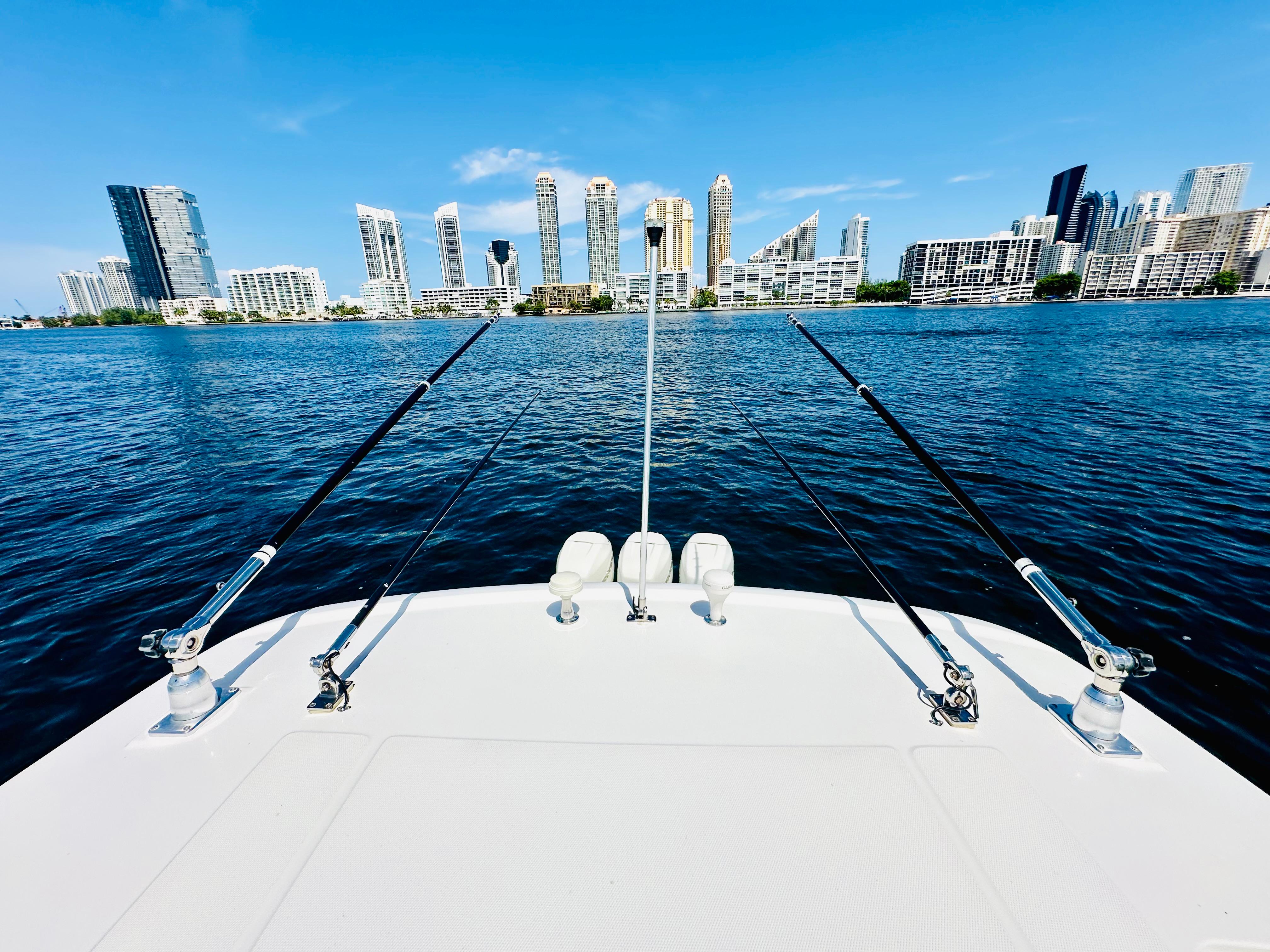 2016 Boston Whaler 350 Outrage boat with fishing rods, city skyline in background.