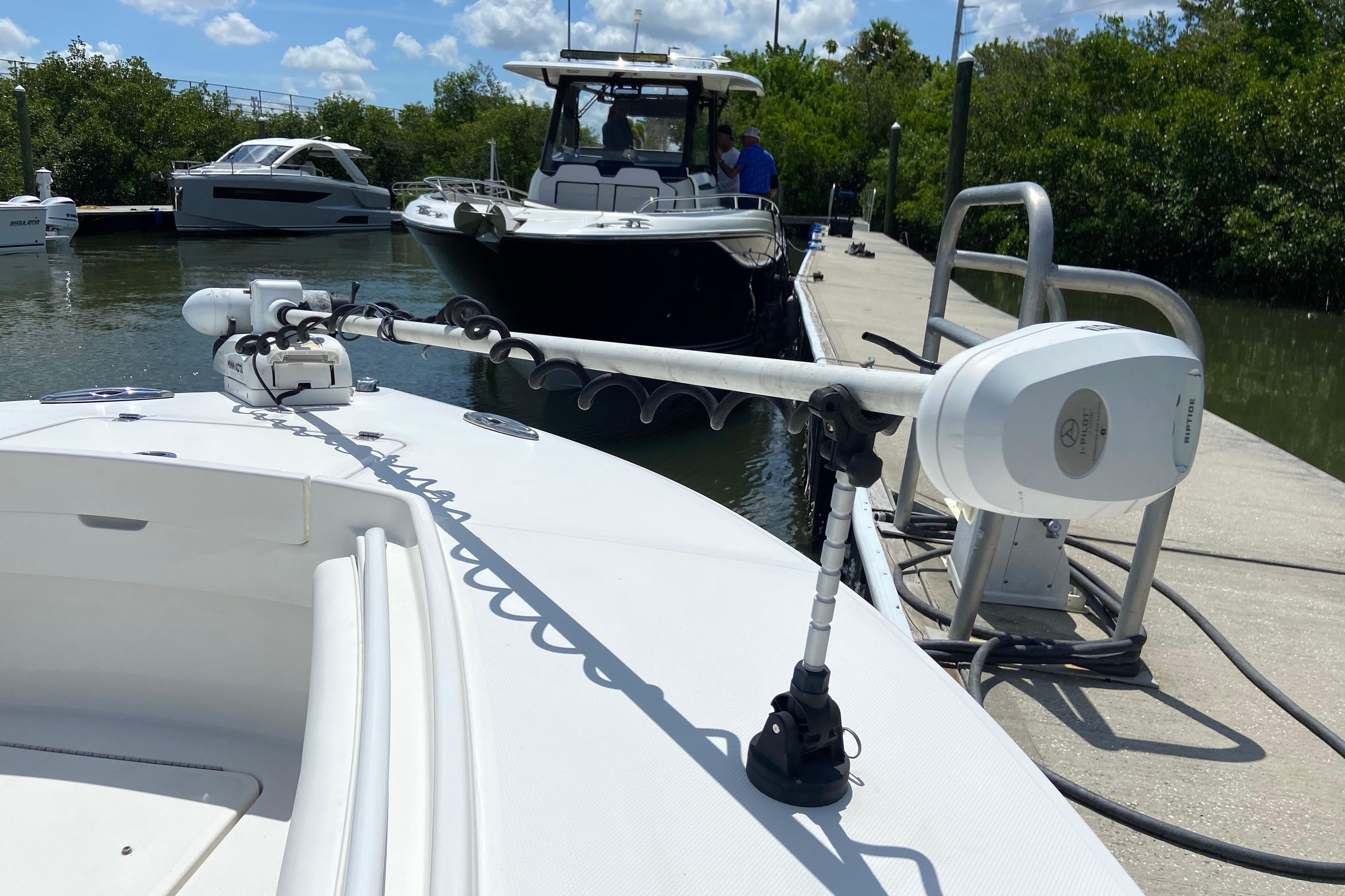 2021 Regulator 28 boat docked with trolling motor, surrounded by other boats and greenery.