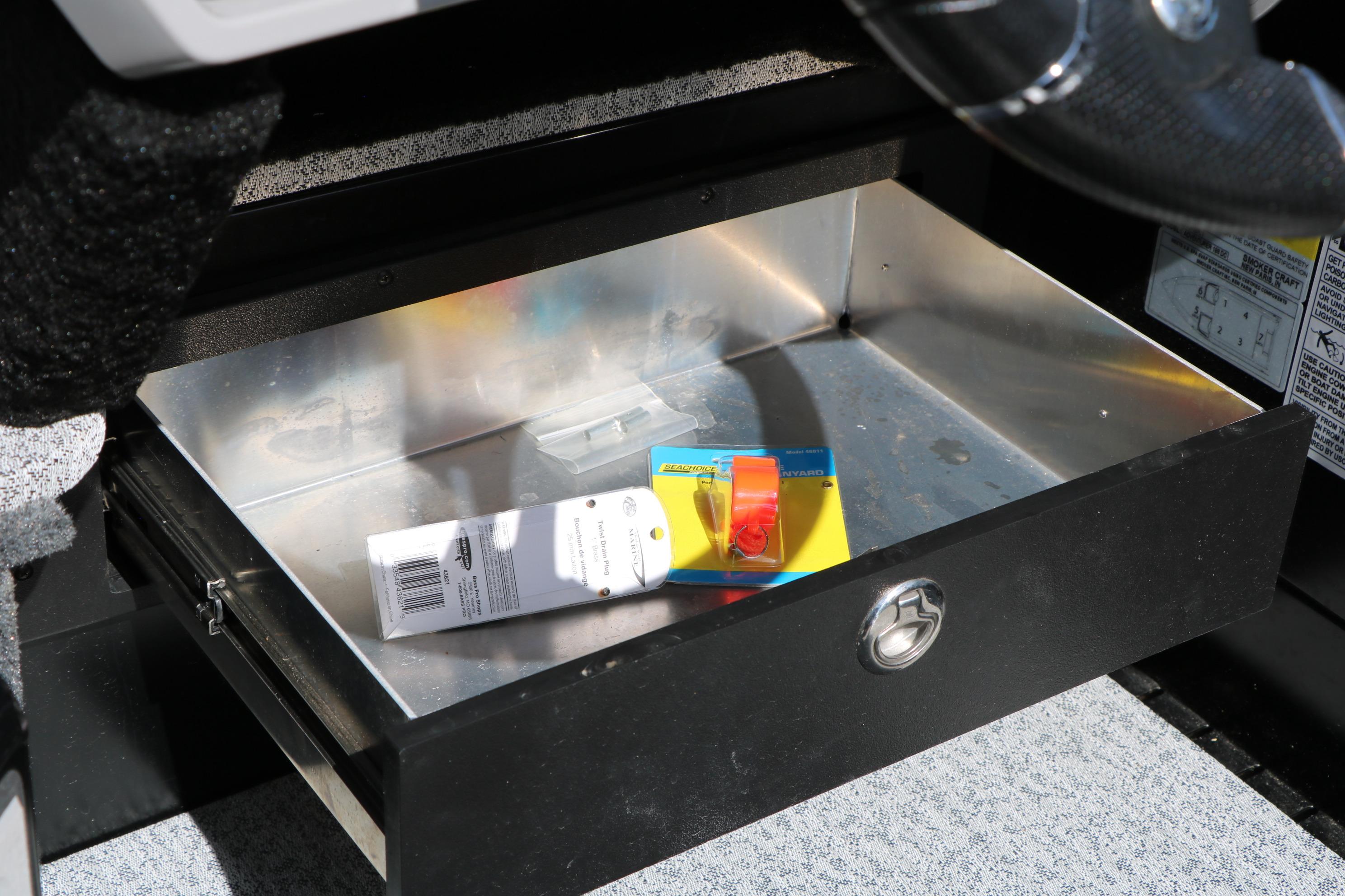 Open storage drawer in 2025 Smoker Craft Adventurer 188 DC boat, containing packaged items.