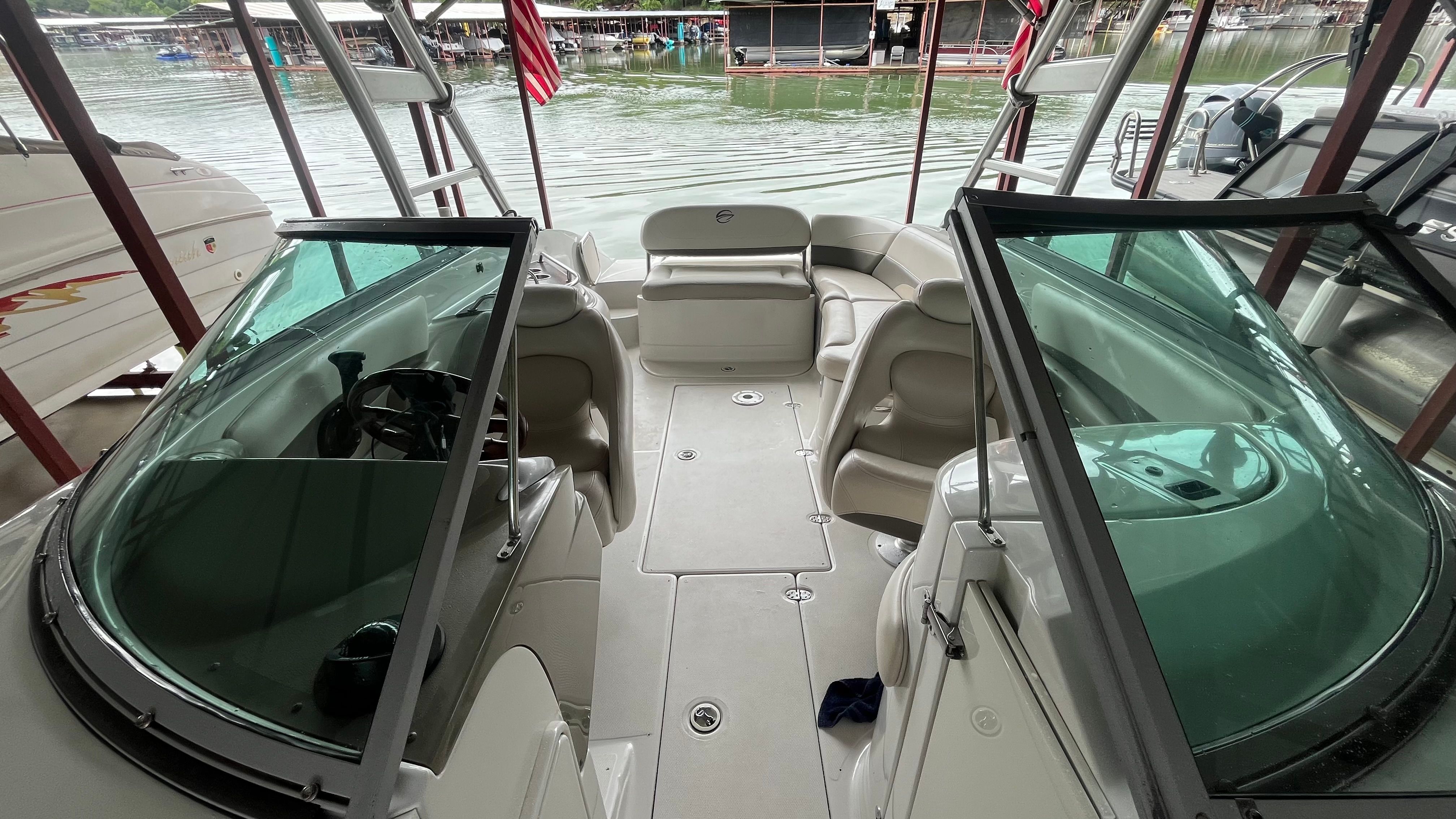 The image shows the cockpit of a 2008 Crownline 252EX boat docked by the water.