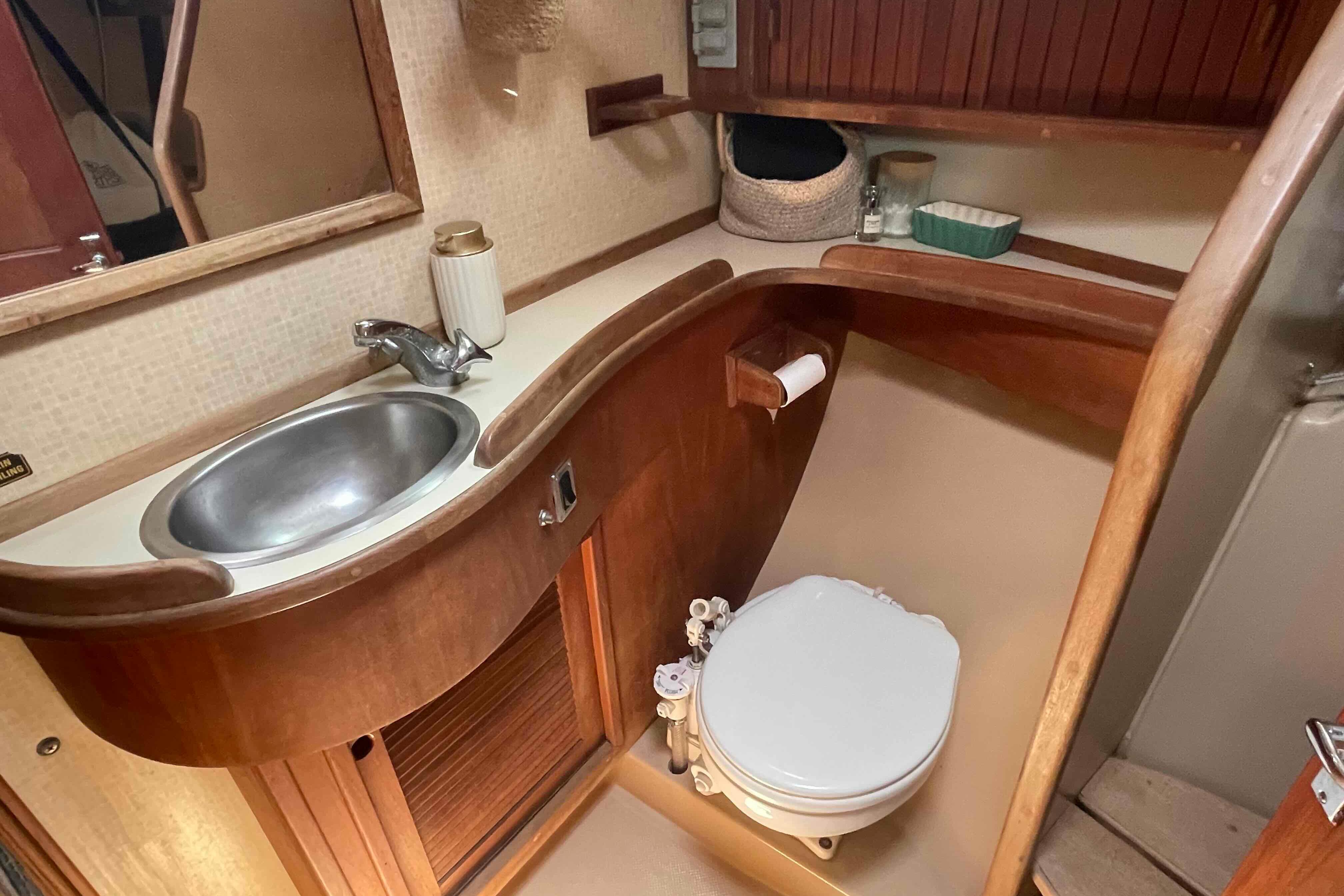 1989 Island Packet 35 yacht bathroom with sink, toilet, and wooden cabinetry.