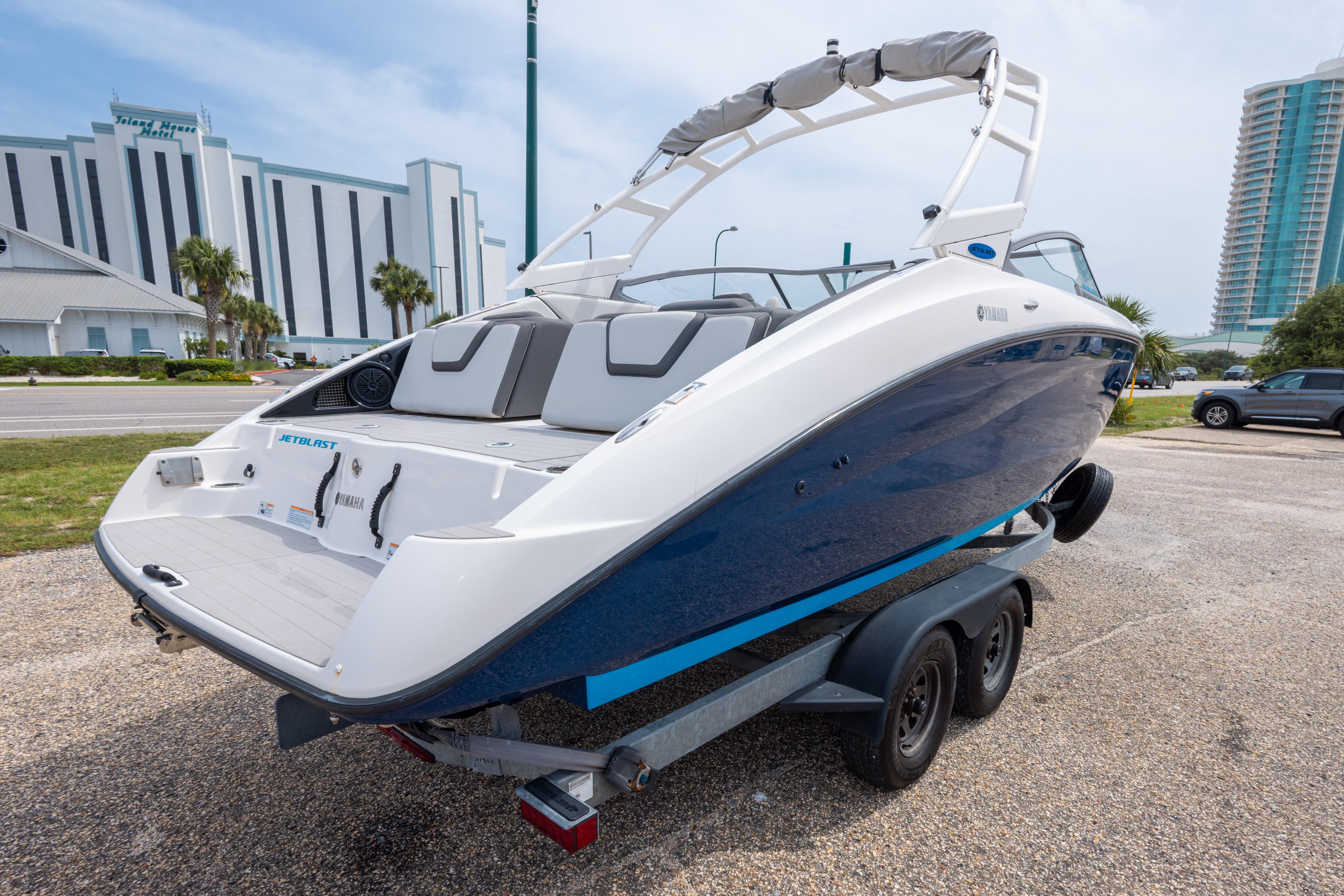 2021 Yamaha Boats AR250 on trailer, parked near modern buildings.
