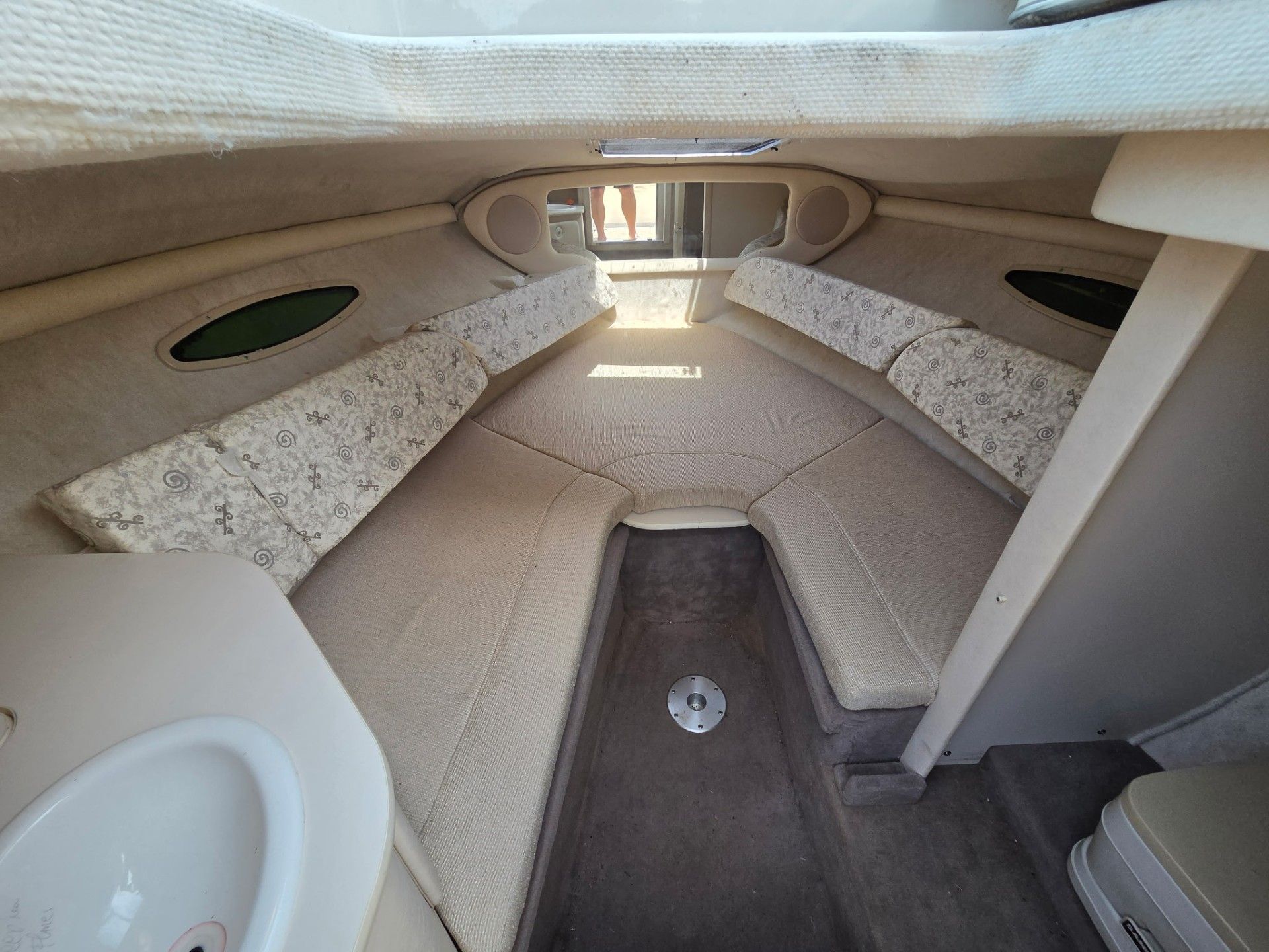 Interior of the 2002 Sea Ray 225 Weekender with cushioned seating areas and a small sink.
