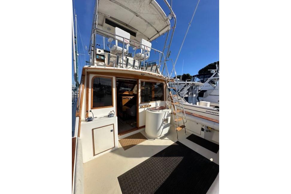 1985 Egg Harbor 33 Sedan boat with upper deck seating and ladder, docked at marina.