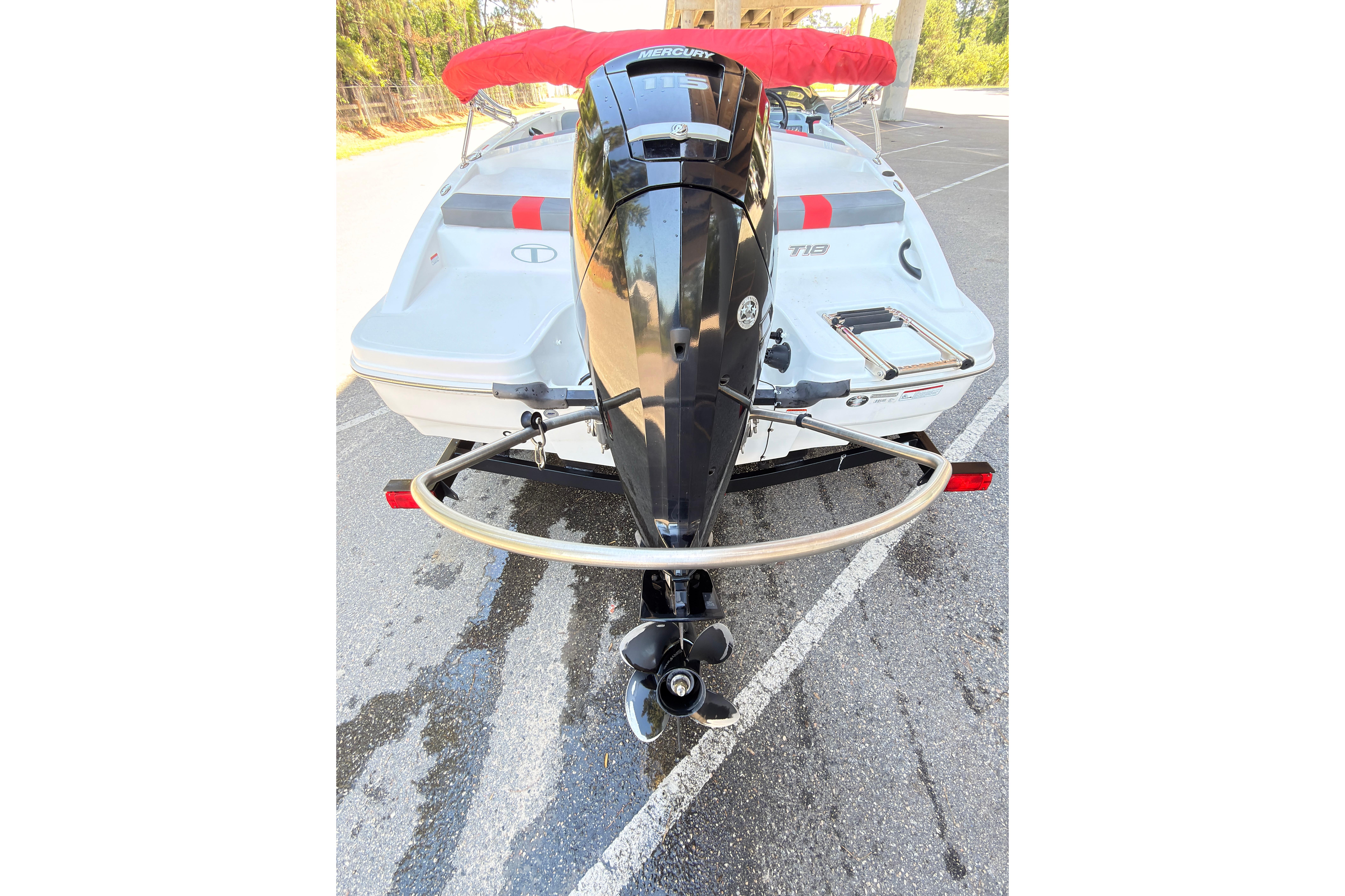 2022 Tahoe T18 boat with outboard motor, parked on asphalt, featuring red canopy.