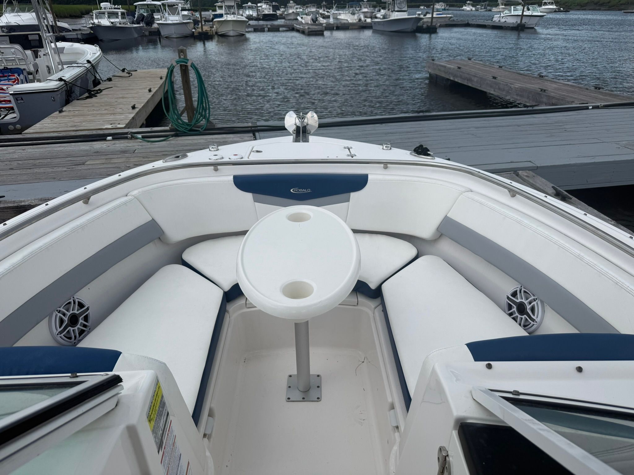 The image shows the bow seating area of a 2022 Robalo R247 Dual Console boat docked.