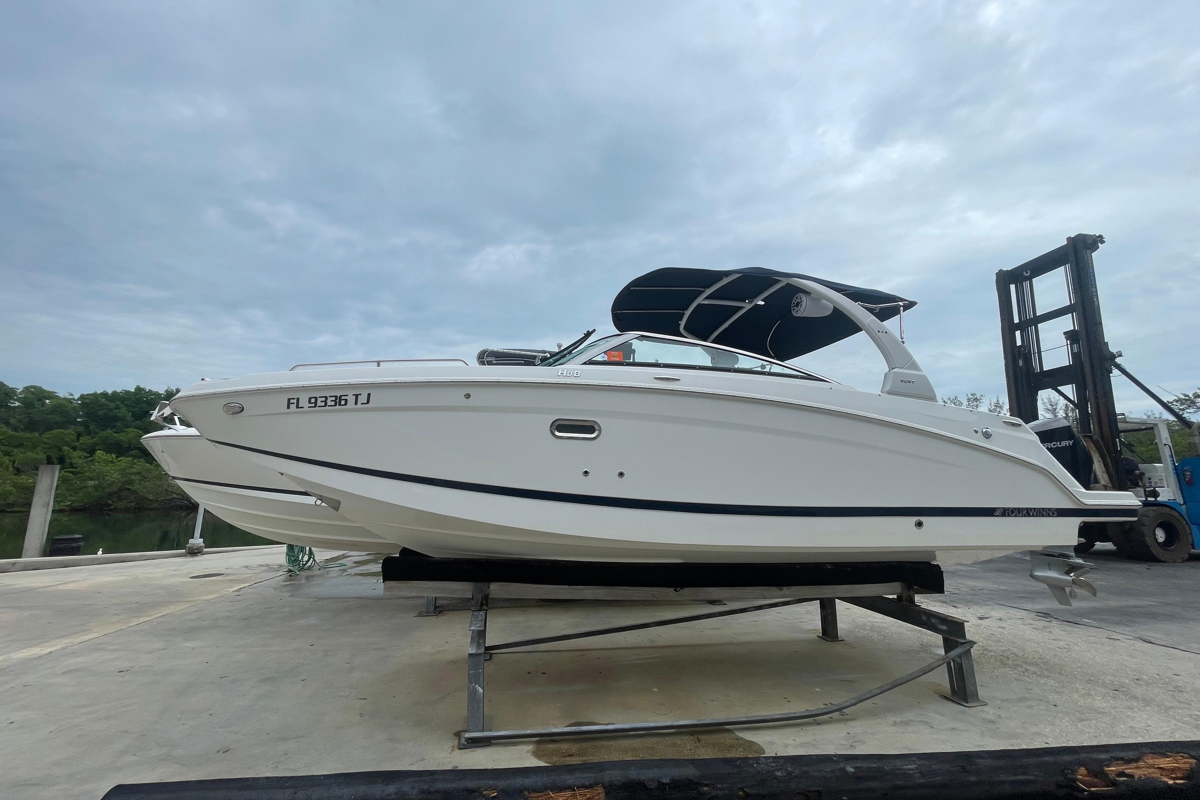 2022 Four Winns HD8 OB boat on a lift, featuring sleek white design and canopy.