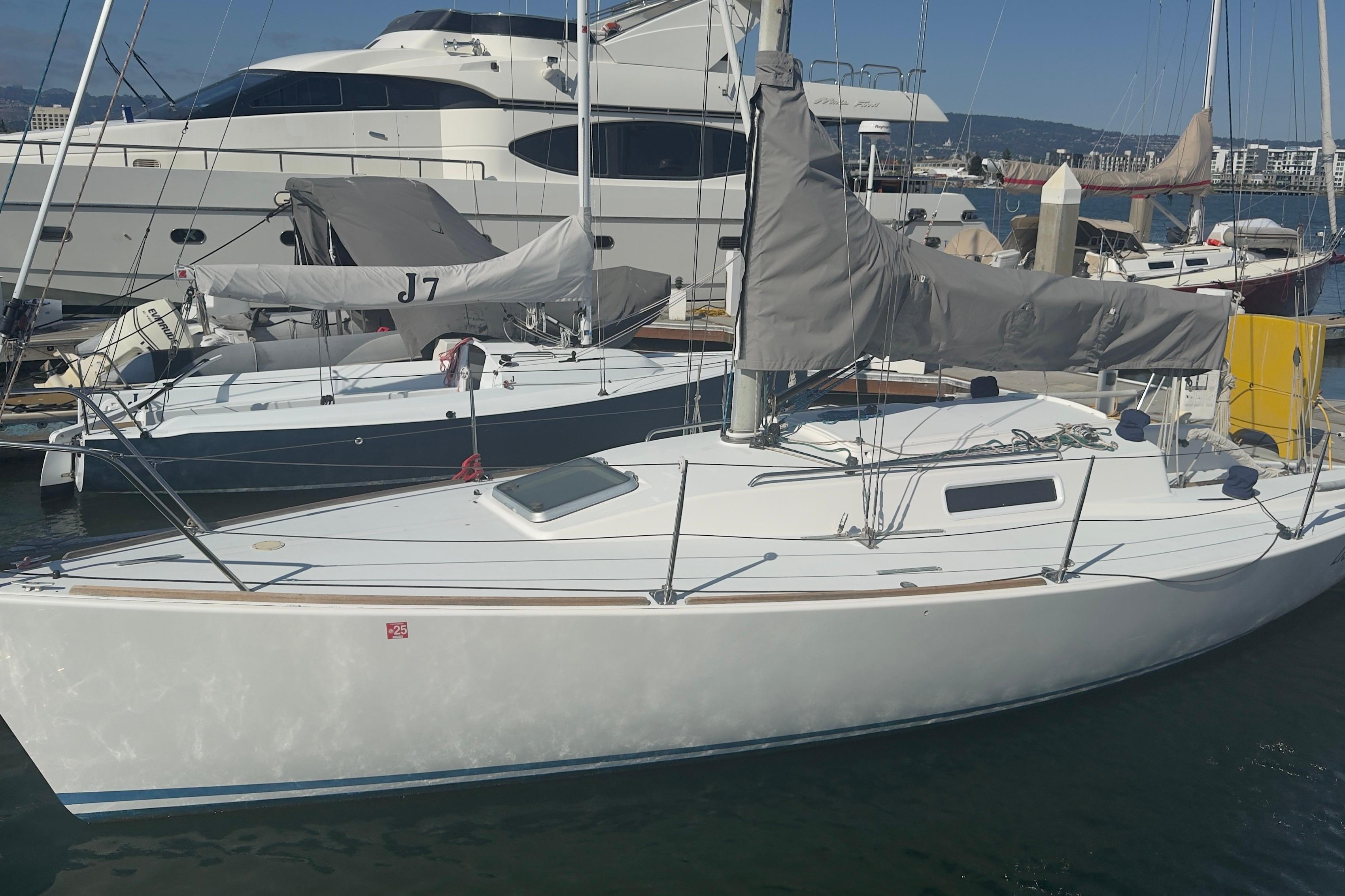 1994 J Boats J/92 sailboat docked in marina, with covered sails and neighboring yachts.