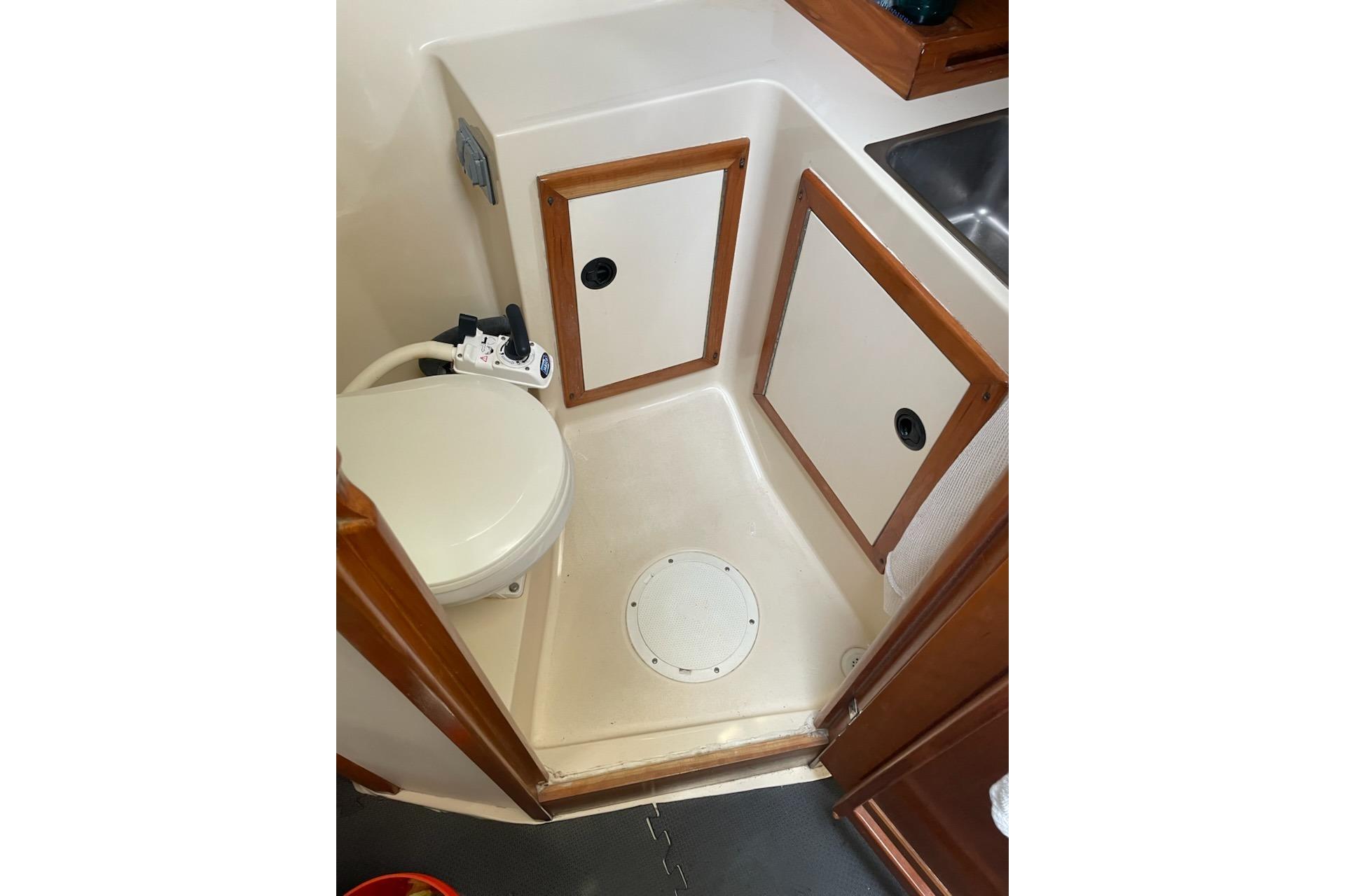 2003 Albin 28 Tournament Express boat bathroom with toilet and storage cabinets.