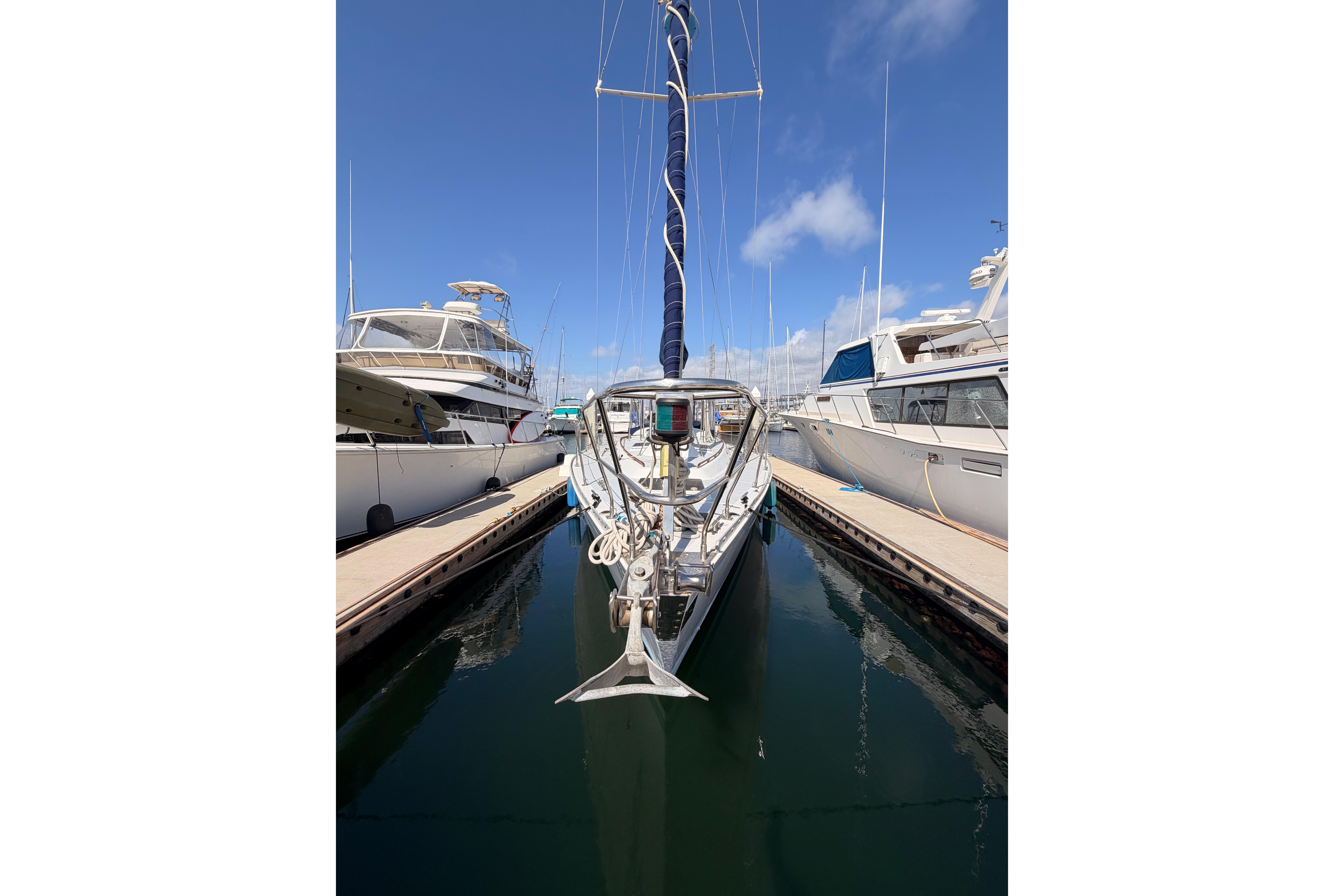 1991 Hylas 51 sailboat docked between yachts under a clear blue sky.