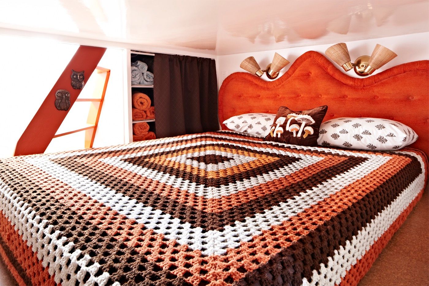 Cozy bedroom with a crocheted blanket and decorative pillows on a houseboat.