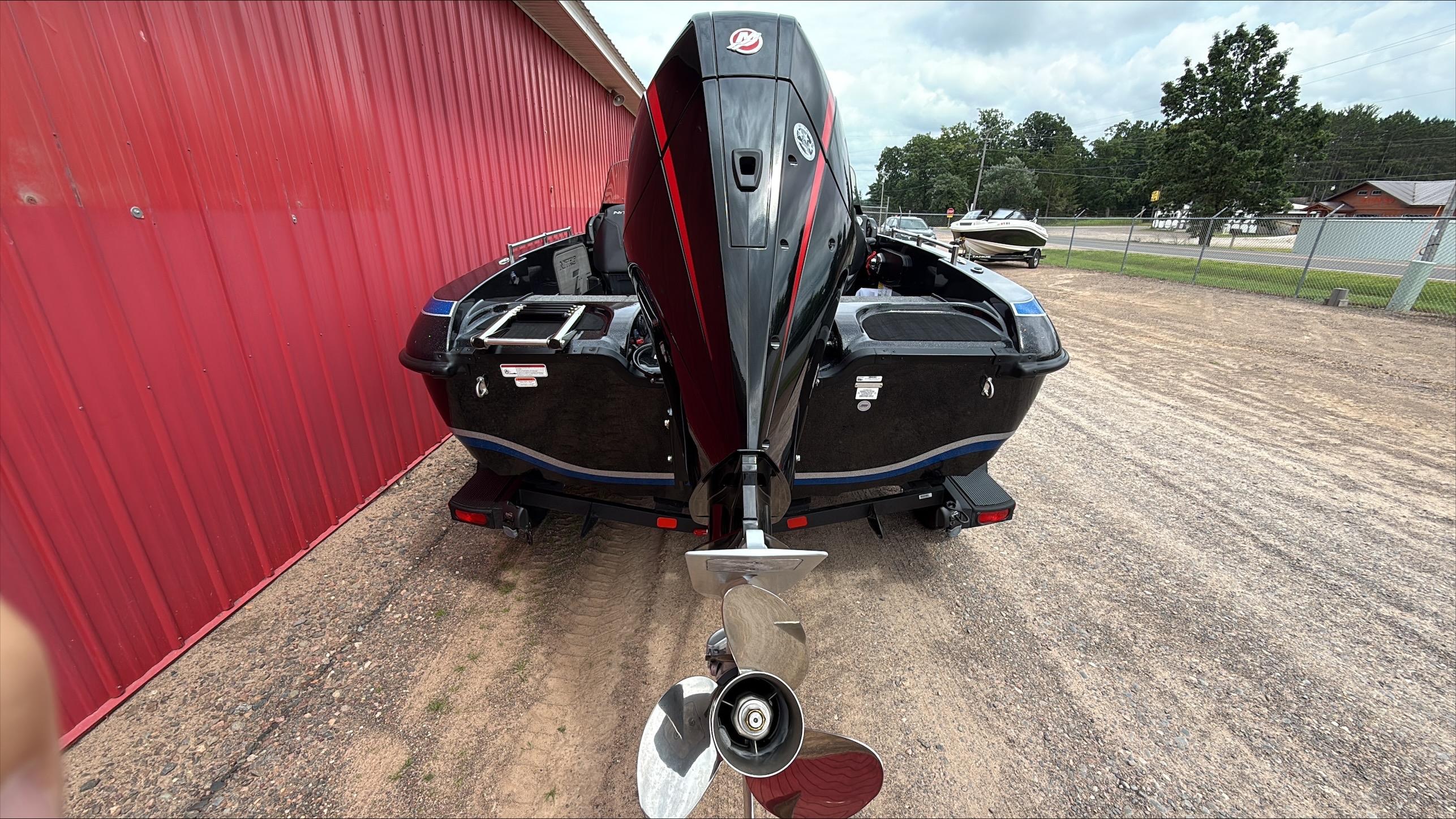 2025 Nitro ZV19 boat with powerful outboard motor, parked beside a red building.