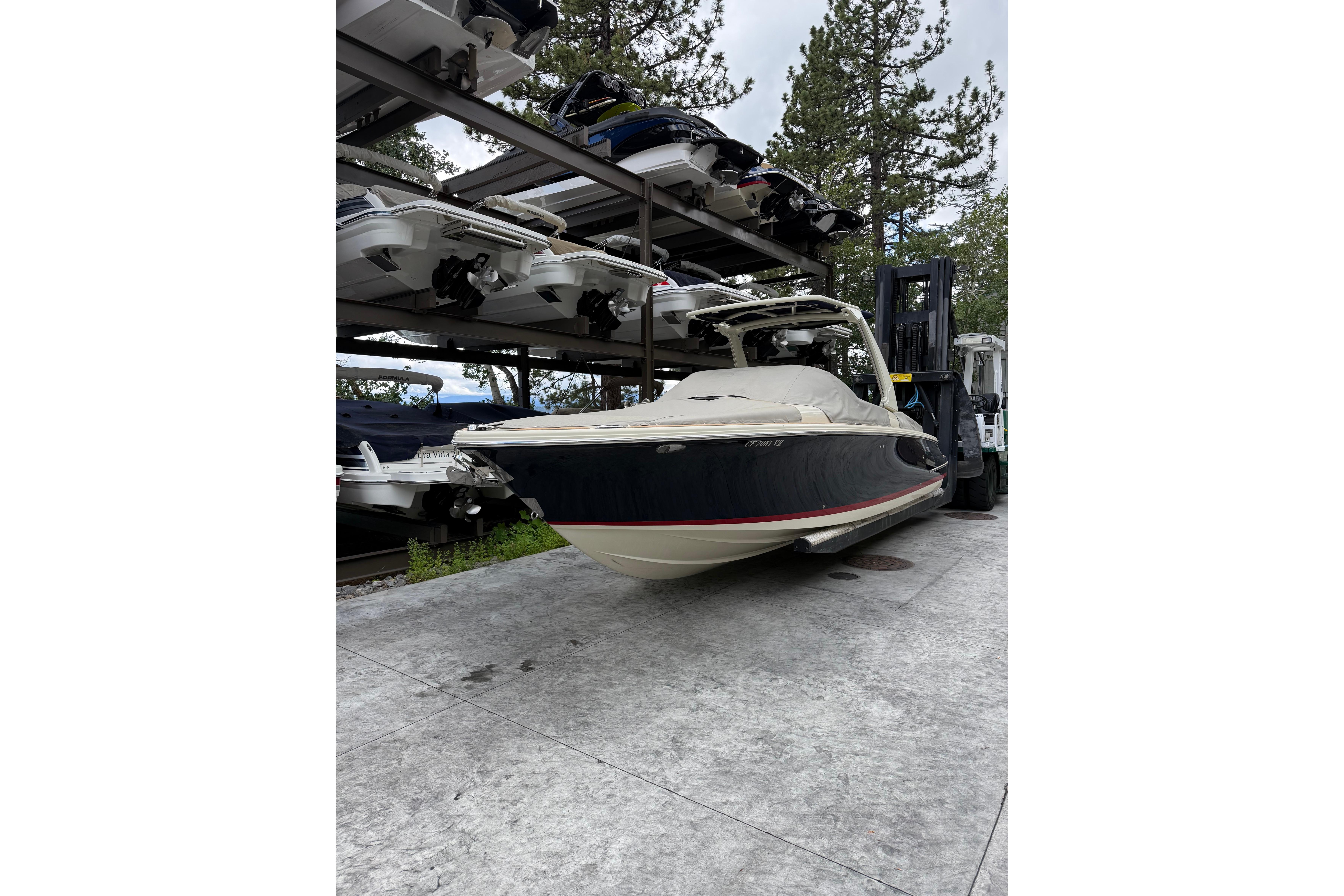 2019 Chris-Craft Launch 28 GT boat stored on a rack, surrounded by trees.