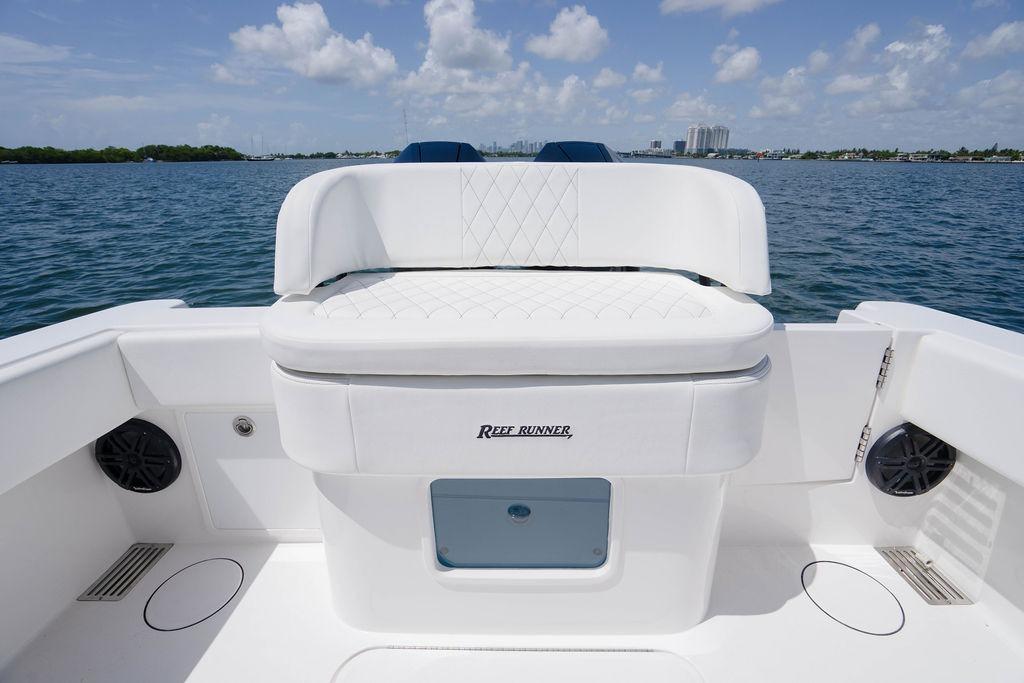 Luxury seating on 2027 Reef Runner 340 boat, featuring sleek white design and ocean backdrop.