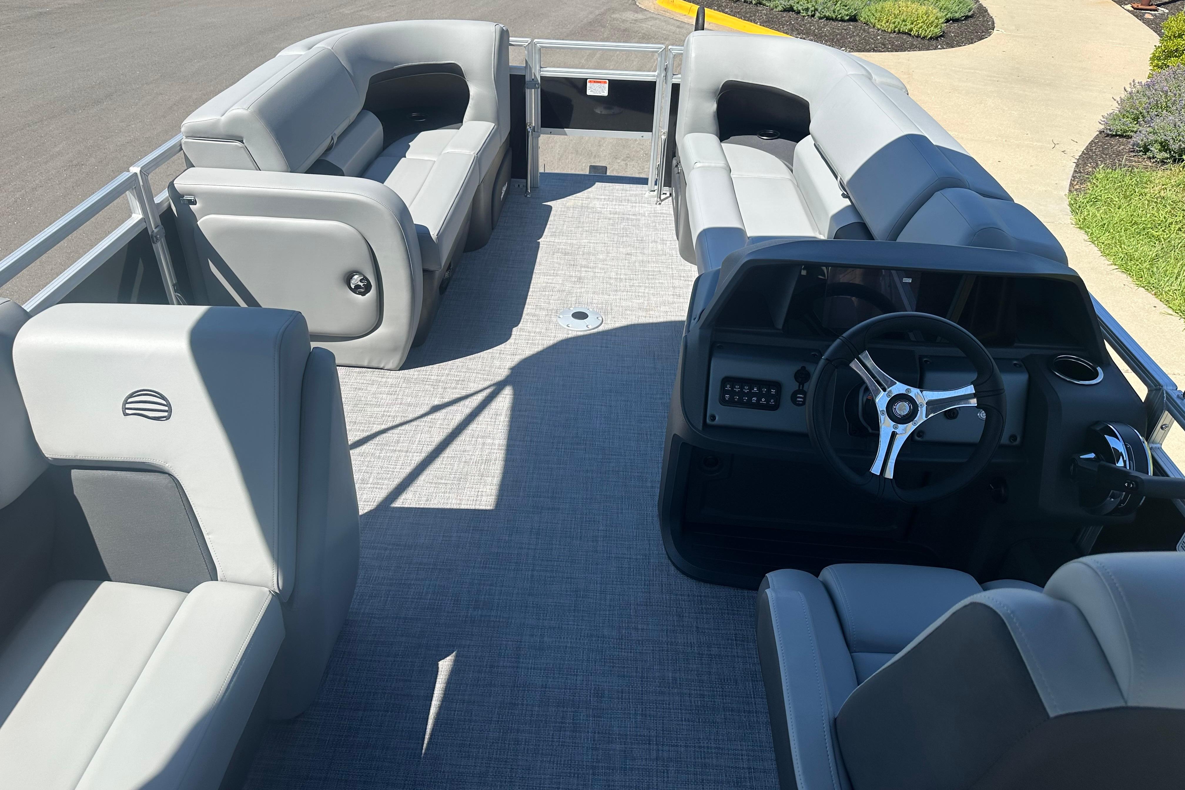 2026 Sun Tracker SportFish 22 DLX pontoon boat interior with gray seating and steering console.