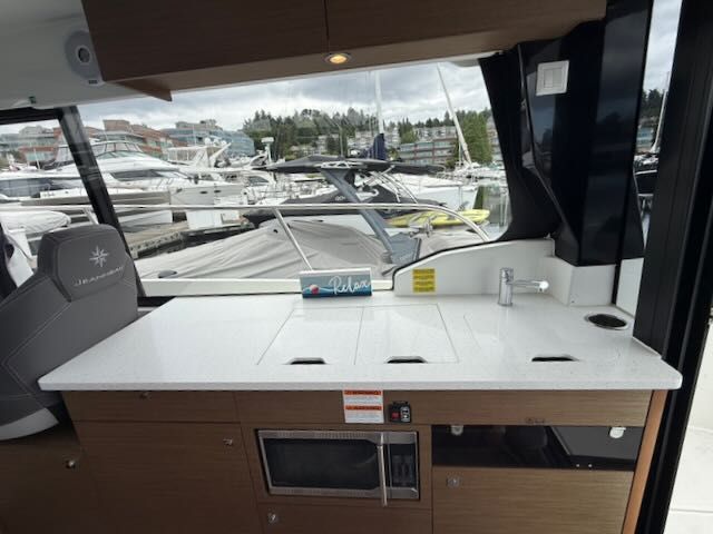 Interior of a Jeanneau NC 1095 with modern kitchen and marina view.