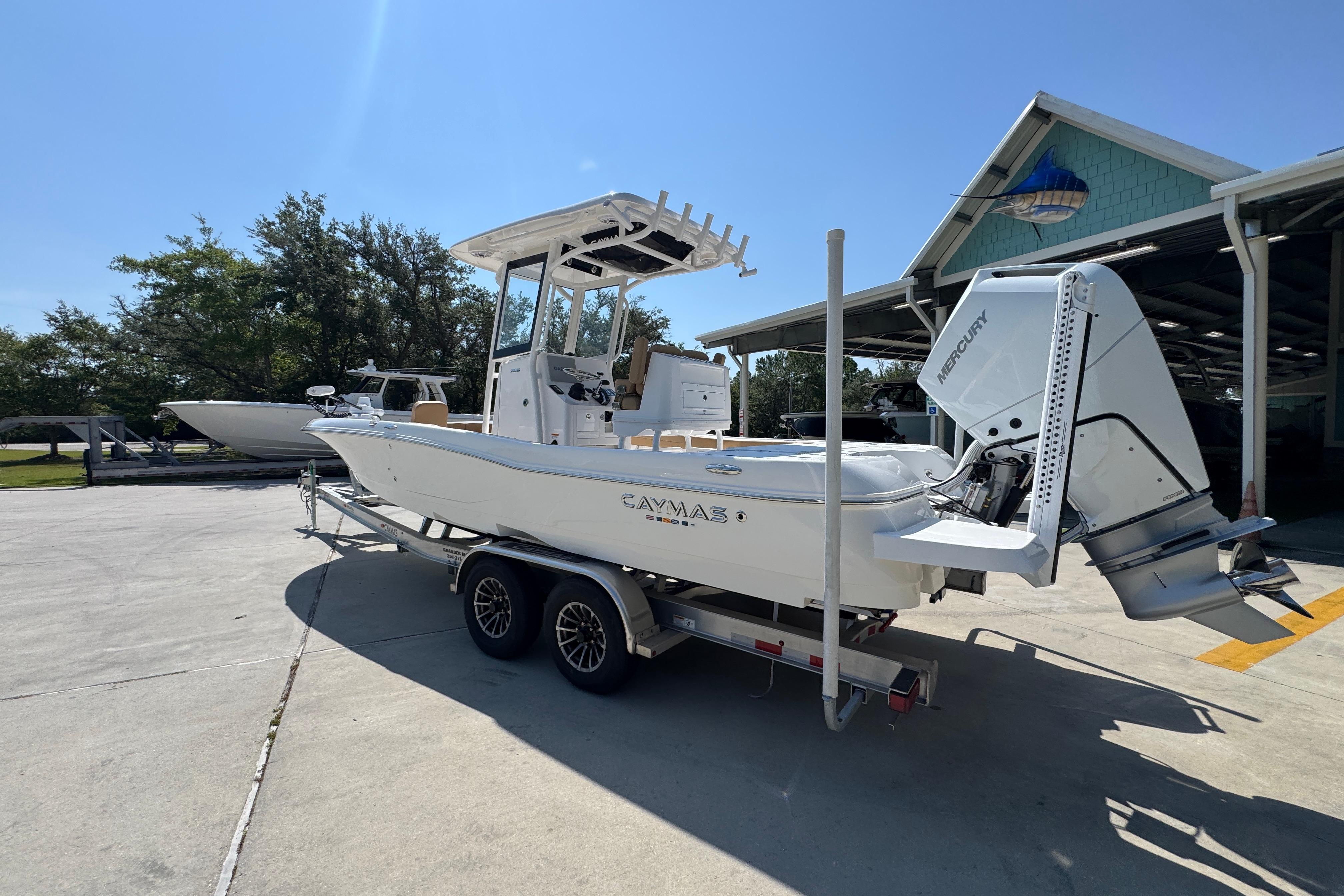 2027 Caymas 26 HB boat on trailer, parked outdoors under clear blue sky.