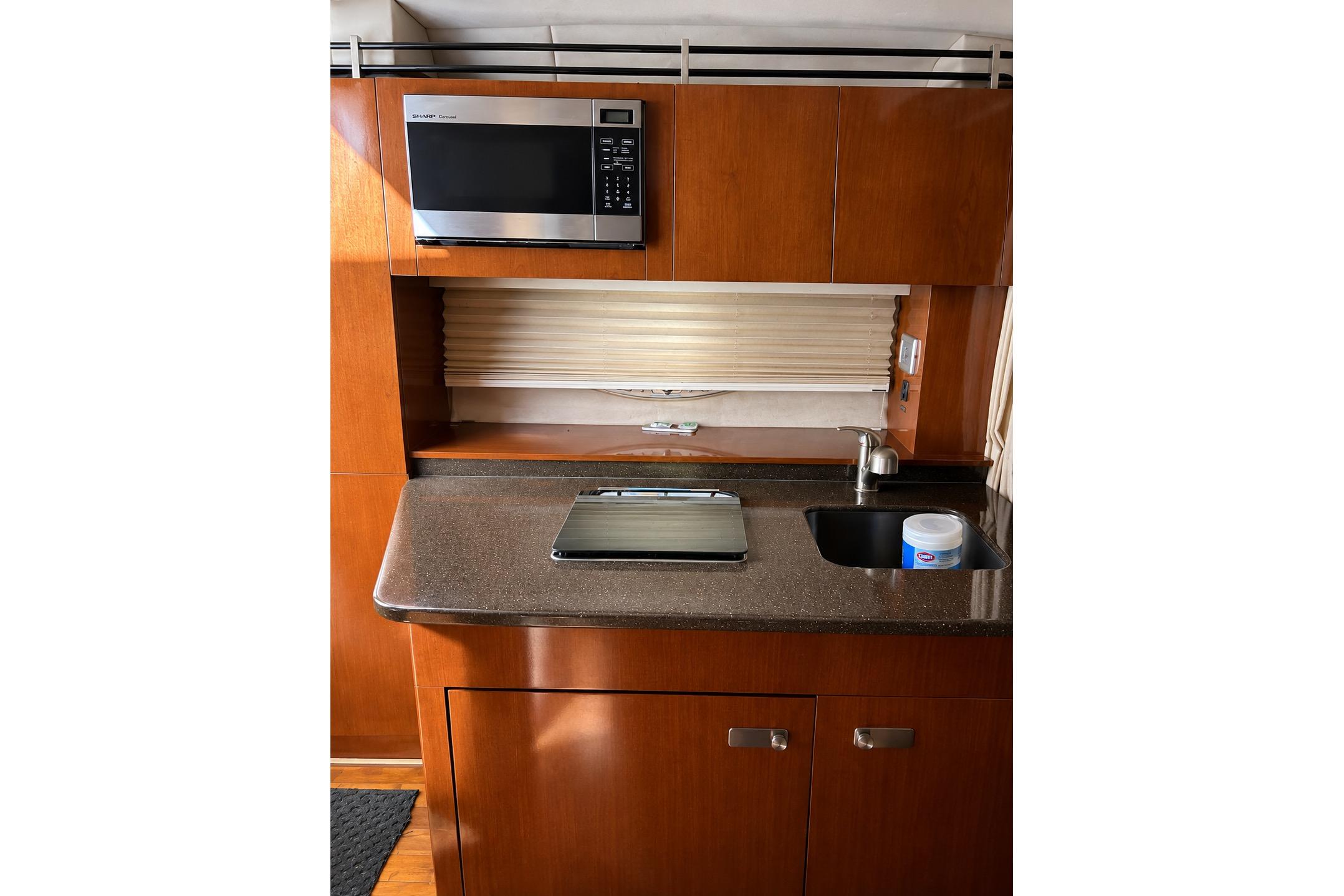Interior of 2012 Sea Ray Sundancer 310, featuring a compact kitchen with microwave and sink.