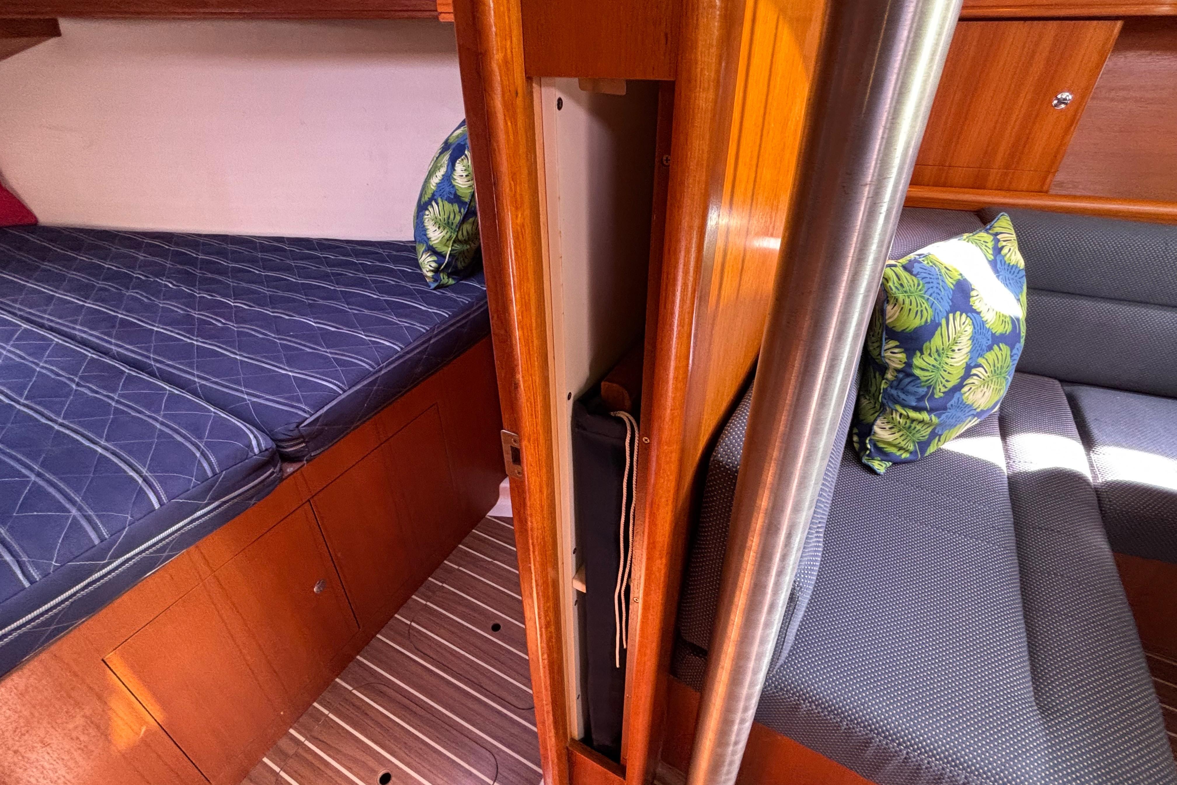 Interior of 2006 Hunter 38 sailboat with cozy bedding and tropical-themed cushions.