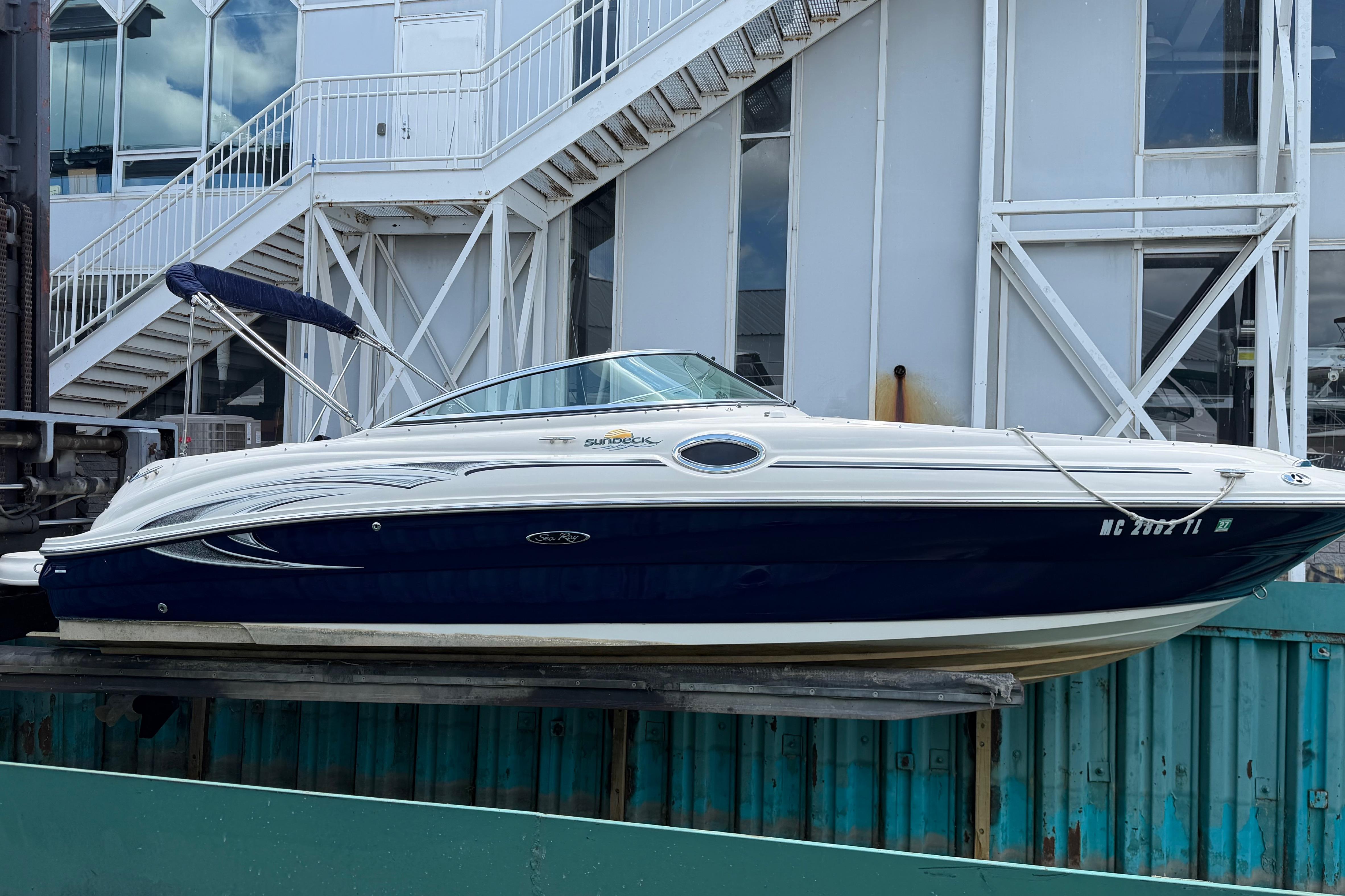 2004 Sea Ray 240 Sundeck boat docked near industrial building.