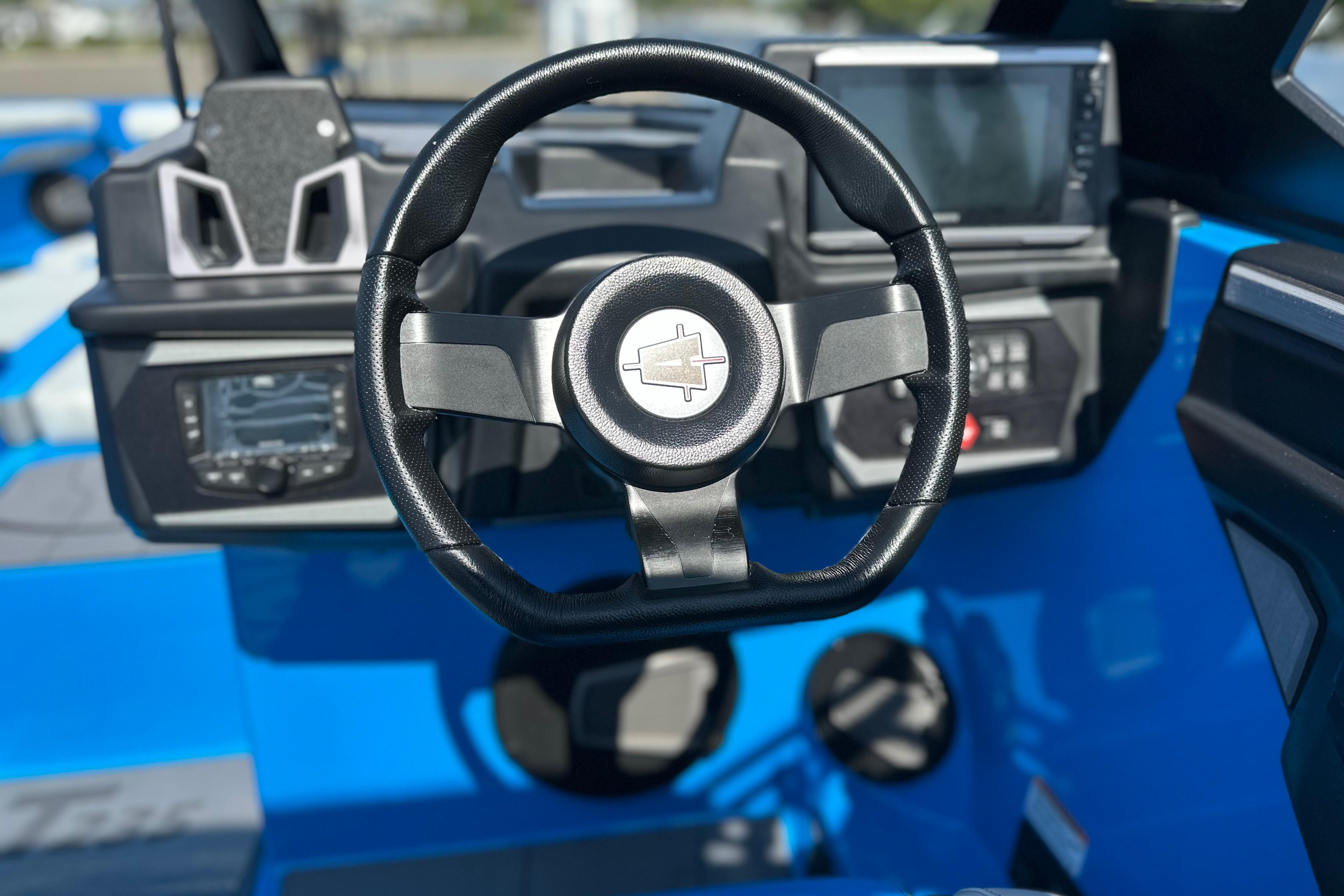 Steering wheel and dashboard of 2026 Axis T235 boat, featuring modern controls and displays.