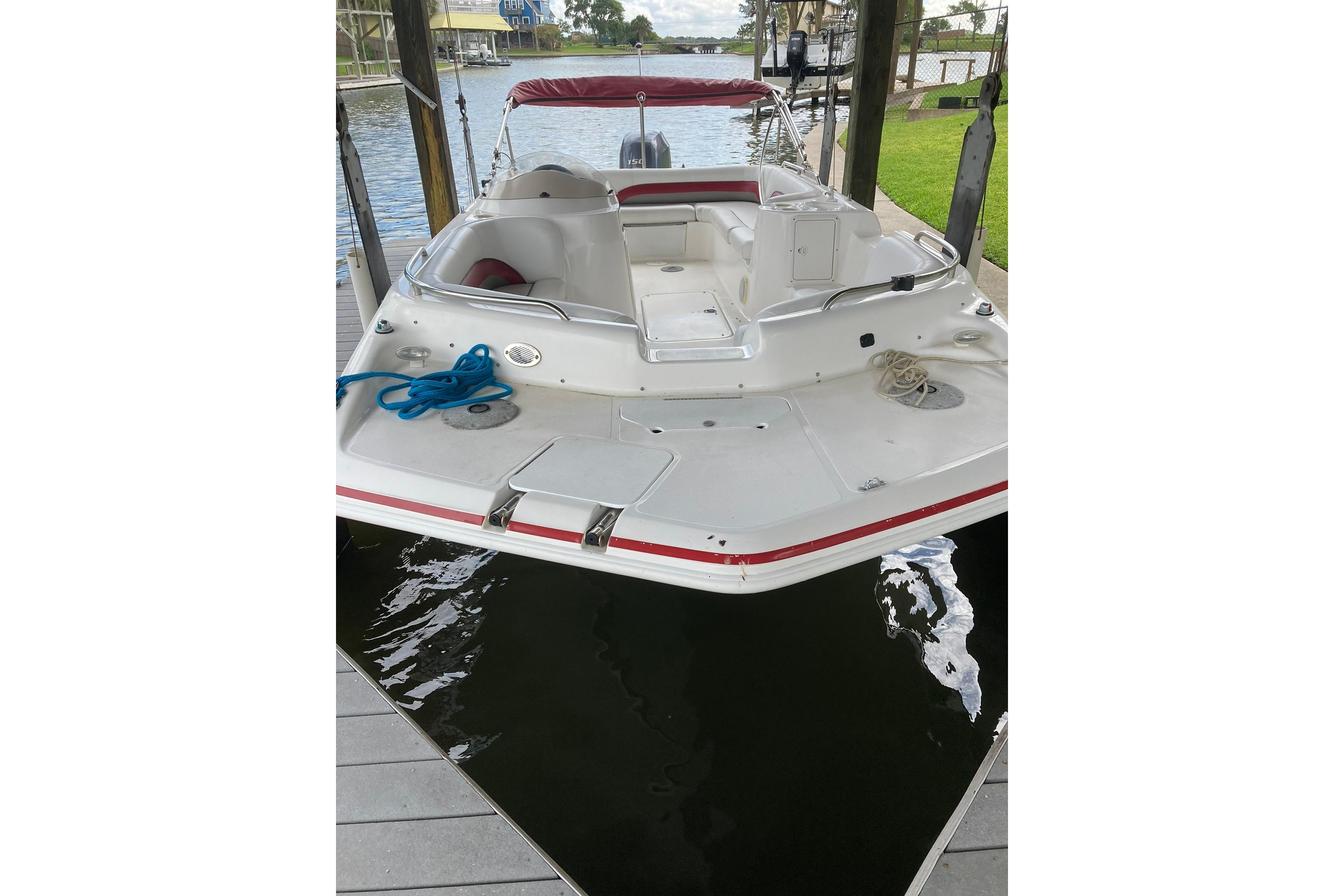 2013 Hurricane SunDeck Sport 201 OB boat docked, featuring spacious seating and sleek design.